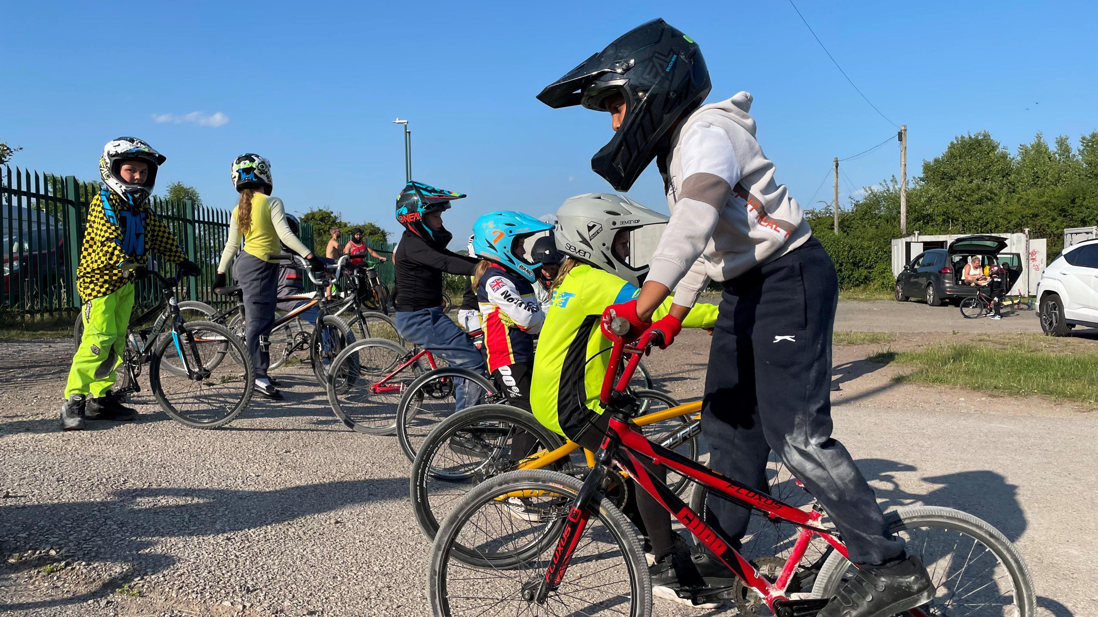 Around six kids on BMX bikes and wearing biker gear.