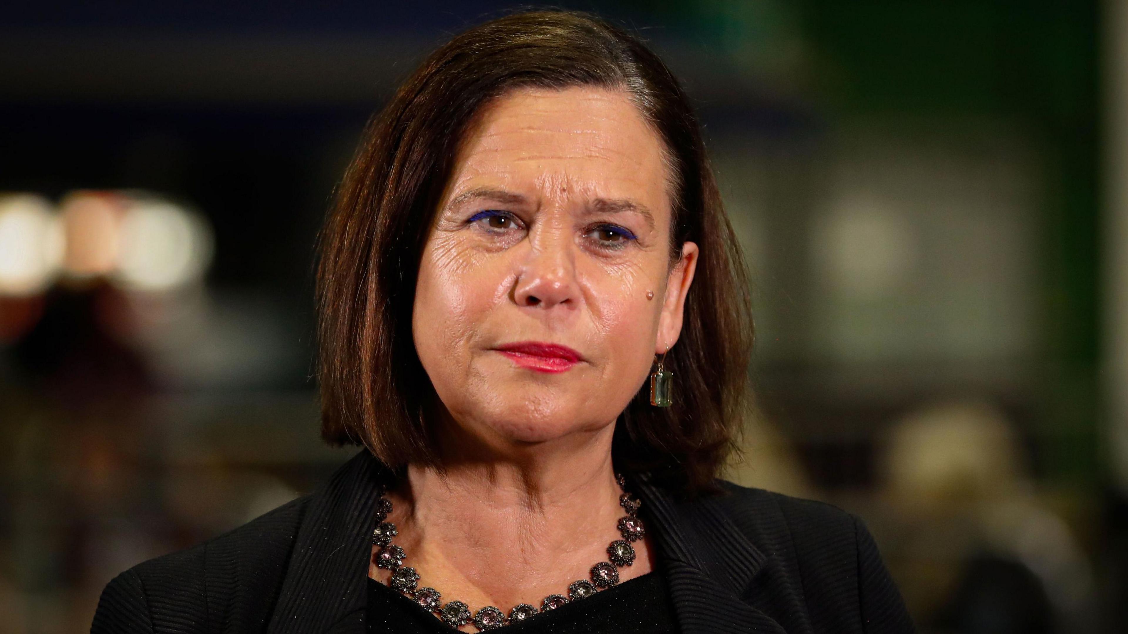 Mary Lou McDonald looking to camera wearing a black suit and necklace