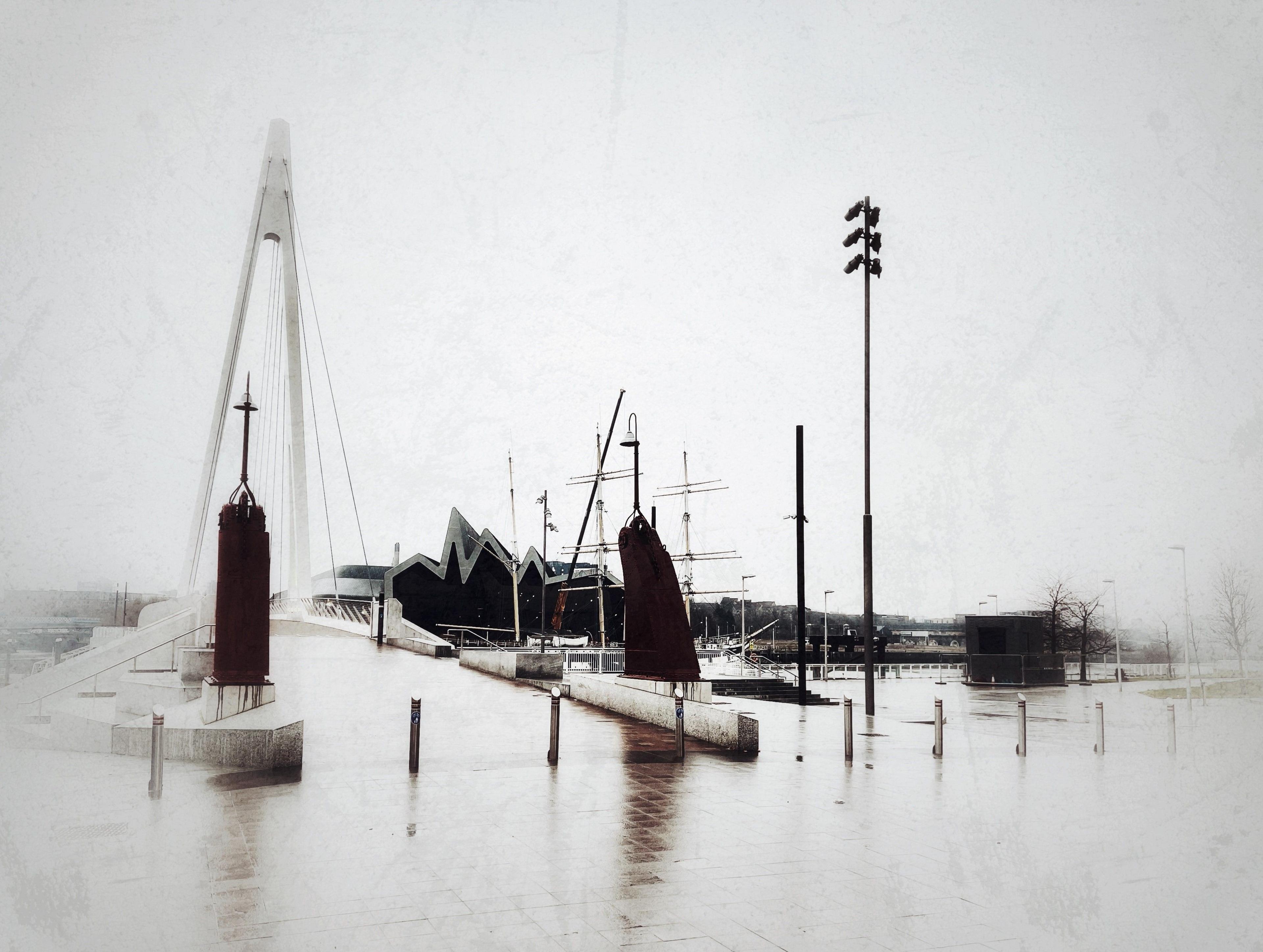 A black and white image on a rainy day of the Govan footbridge with the Riverside museum in the distance