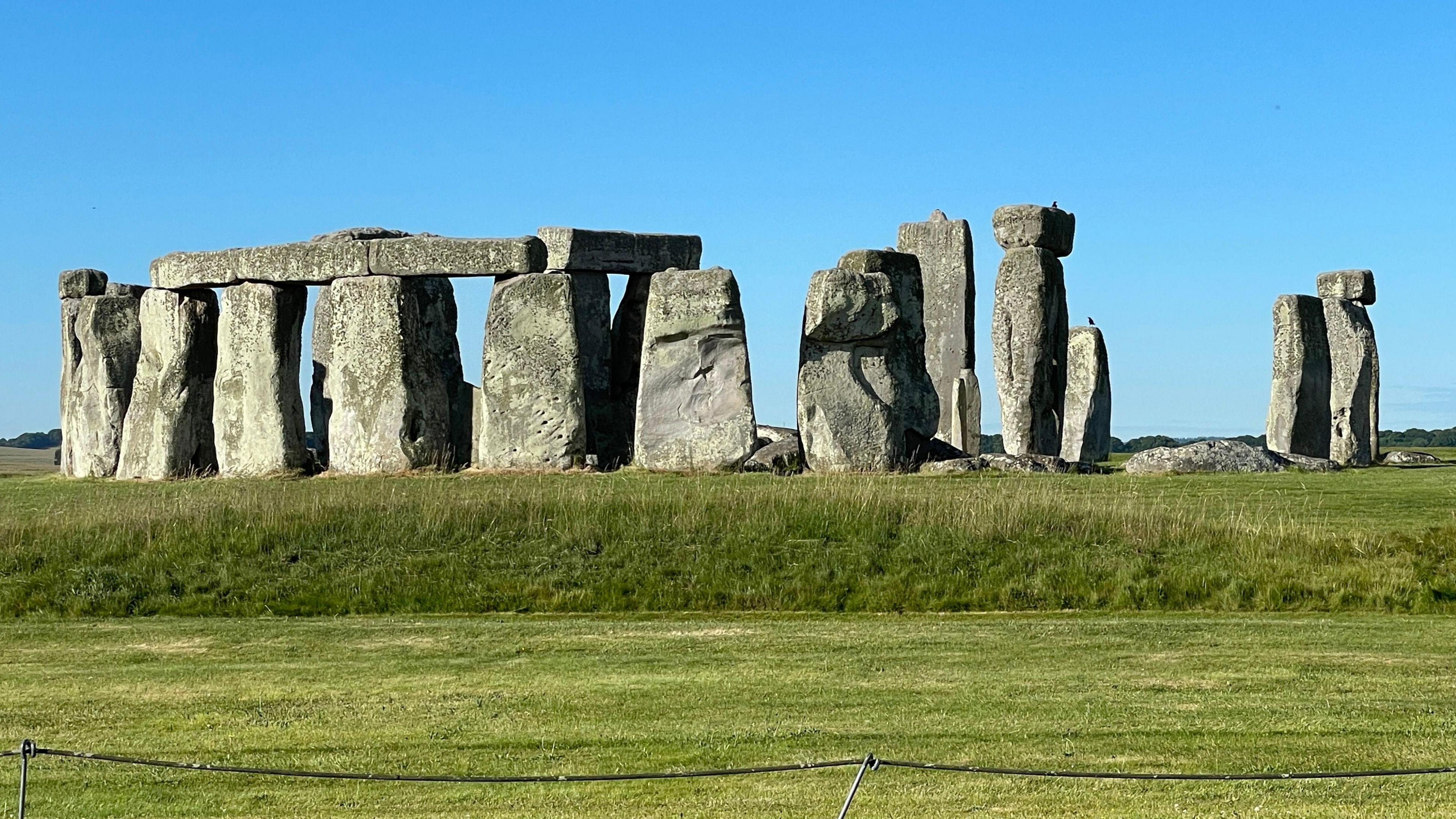 Stonehenge on a sunny day - blue sky and green grass around the large grey standing stones