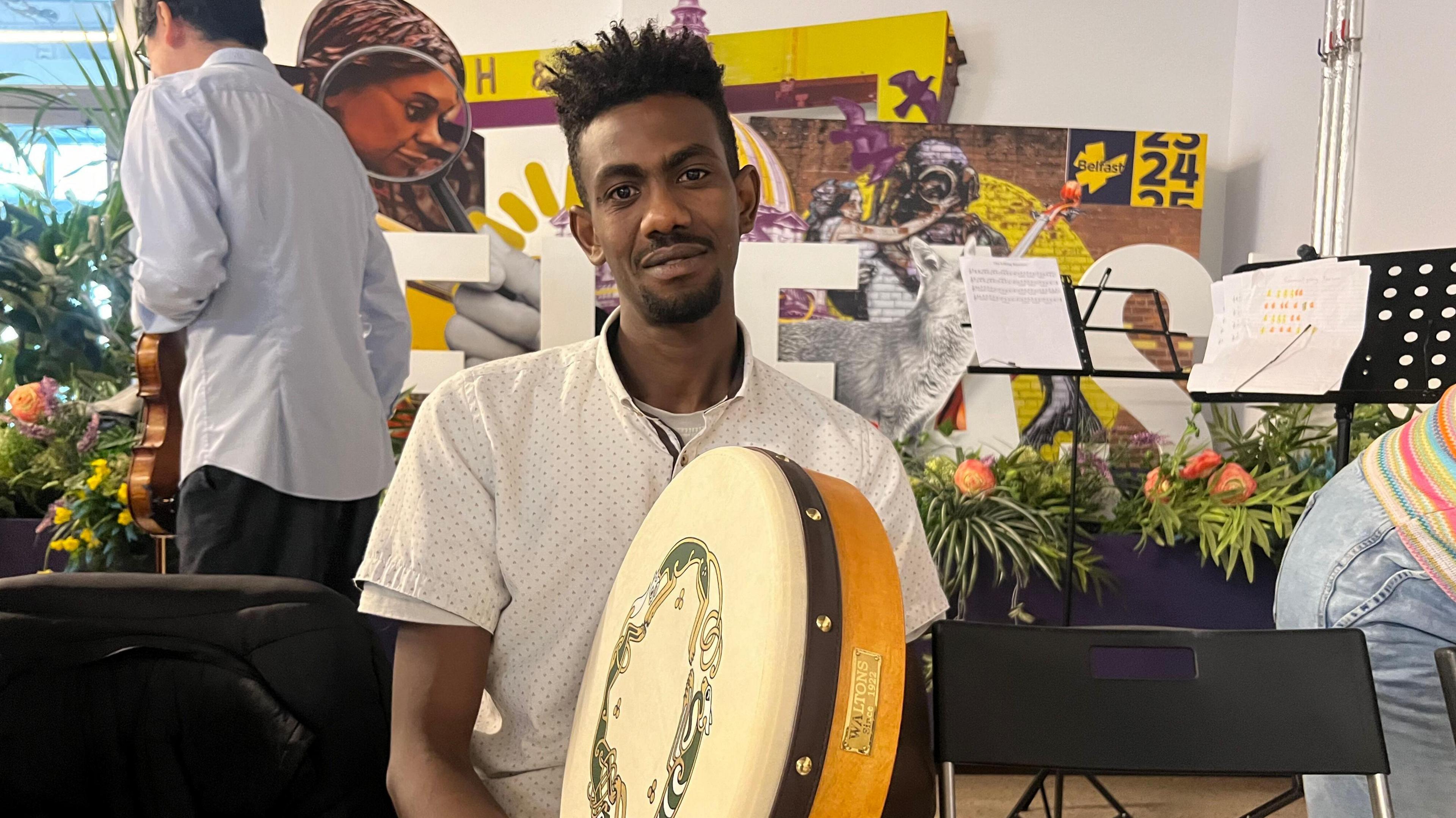 Man in his twenties starting at the camera with the Irish instrument, Bodhrán 