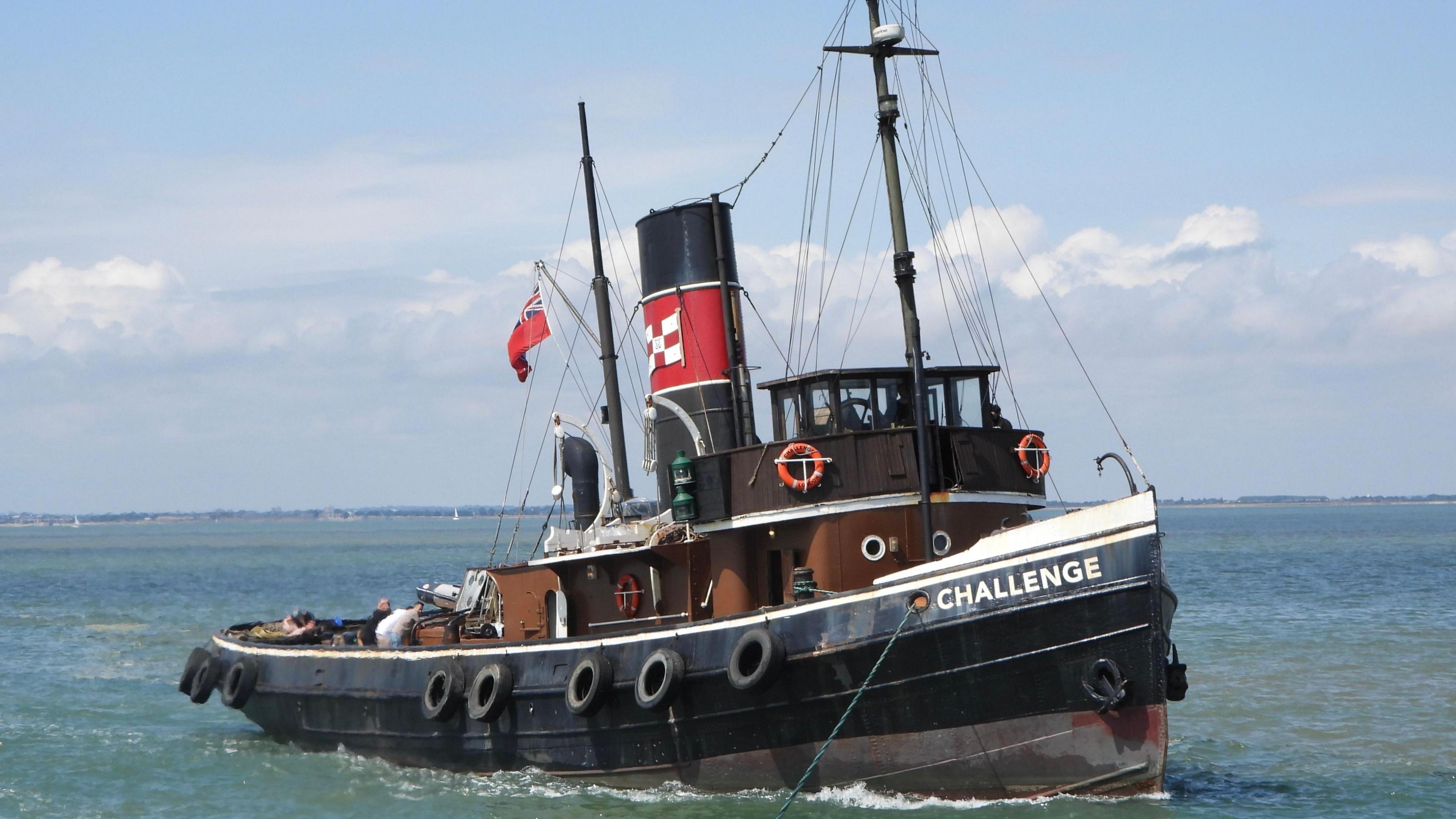 A steam tug vessel, name Challenge, is sailing along a river