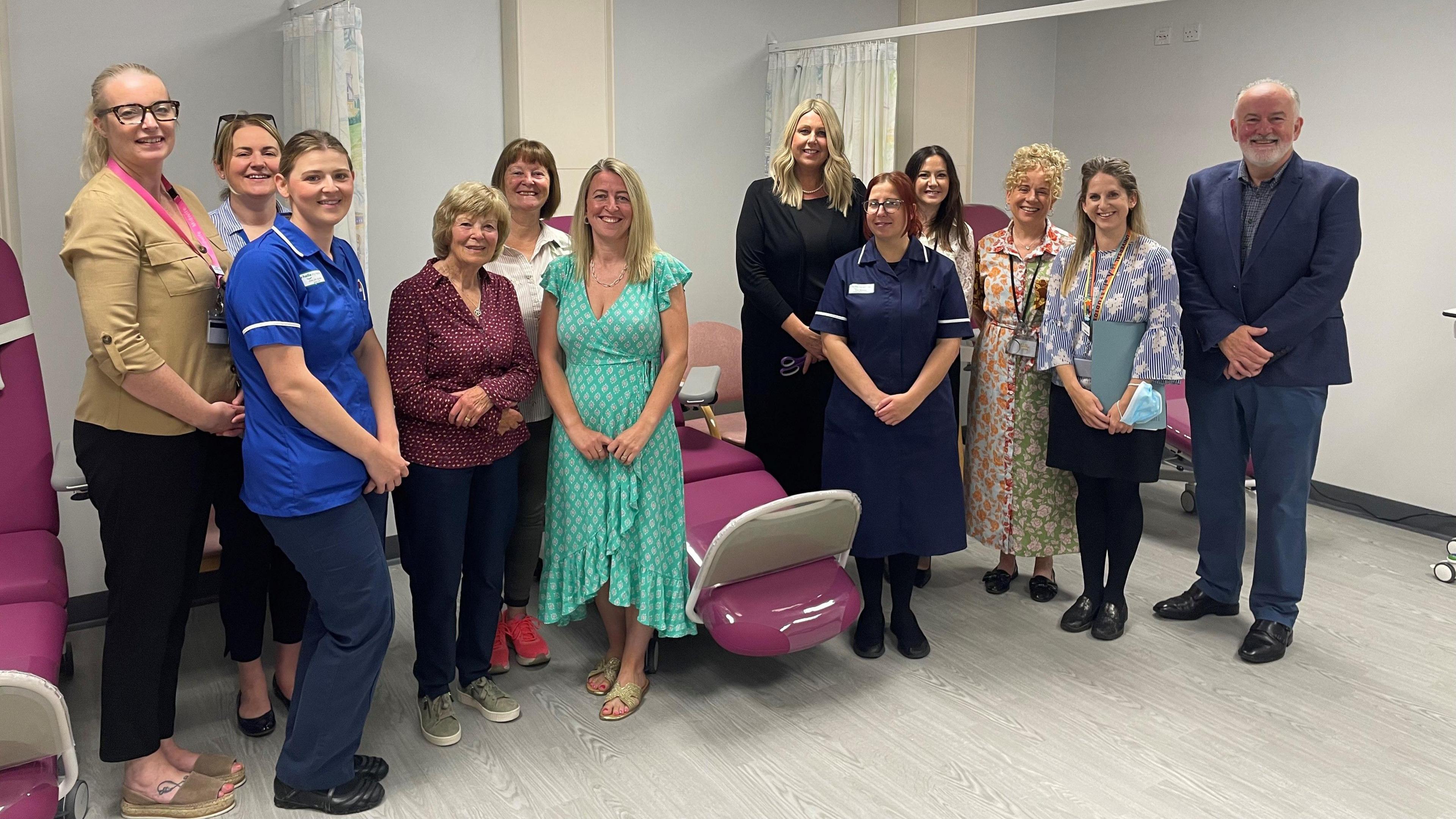 A group of 10 women and one man stood smiling in a new hospital ward