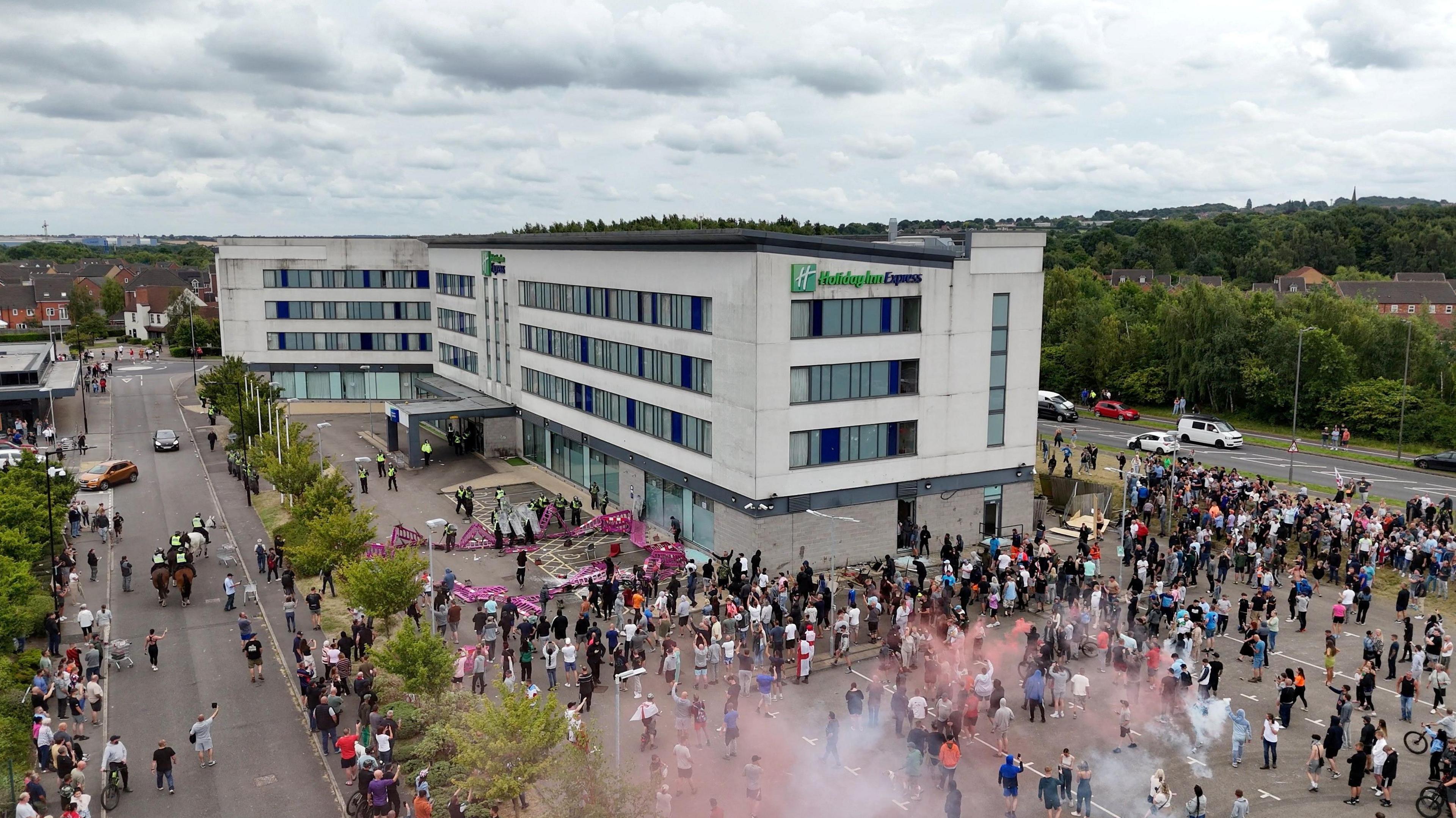 A drone view shows demonstrators protesting outside a hotel as police officers stand guard in Rotherham, Britain.