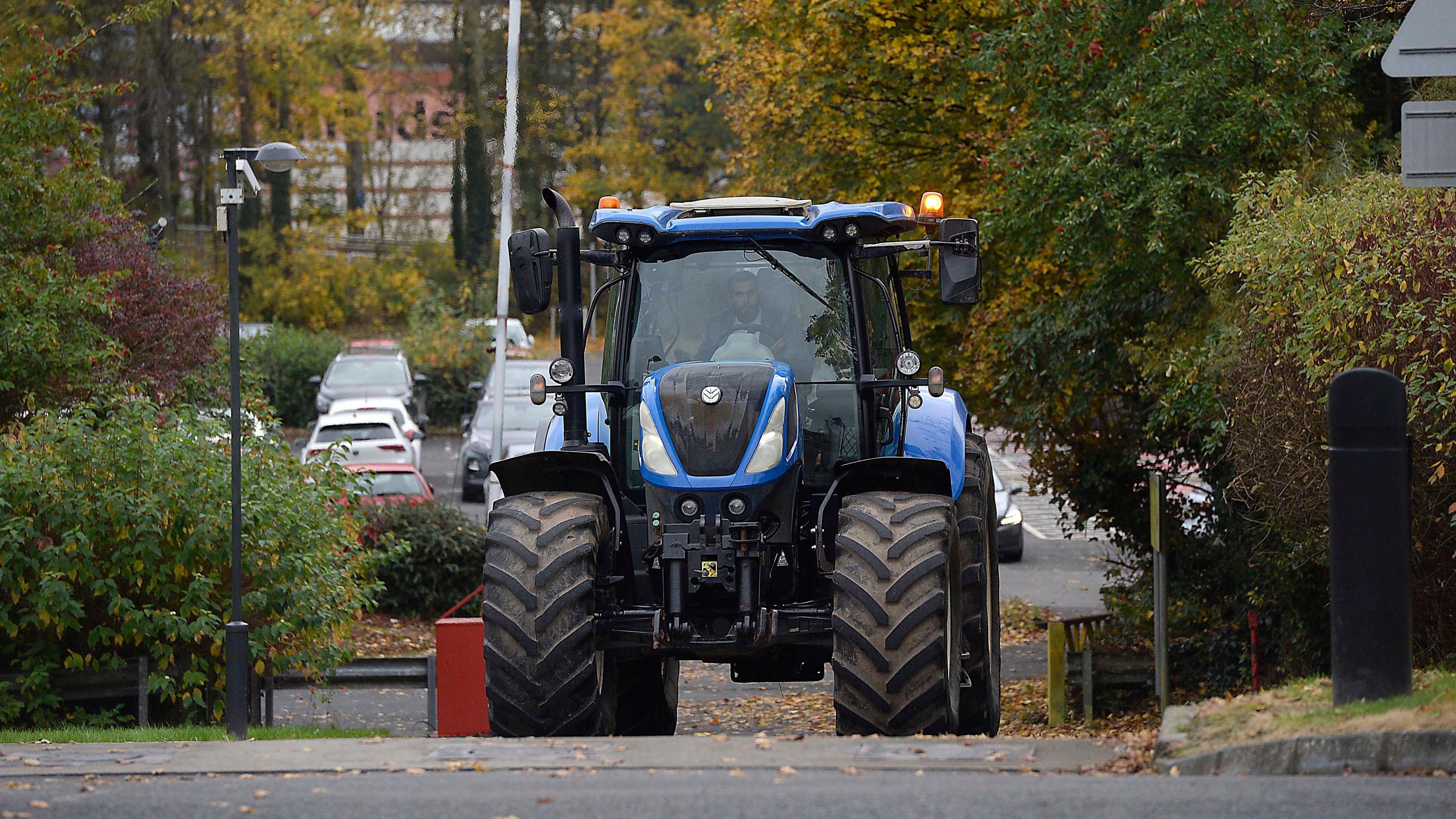 a large blue tractor in a wooded car park