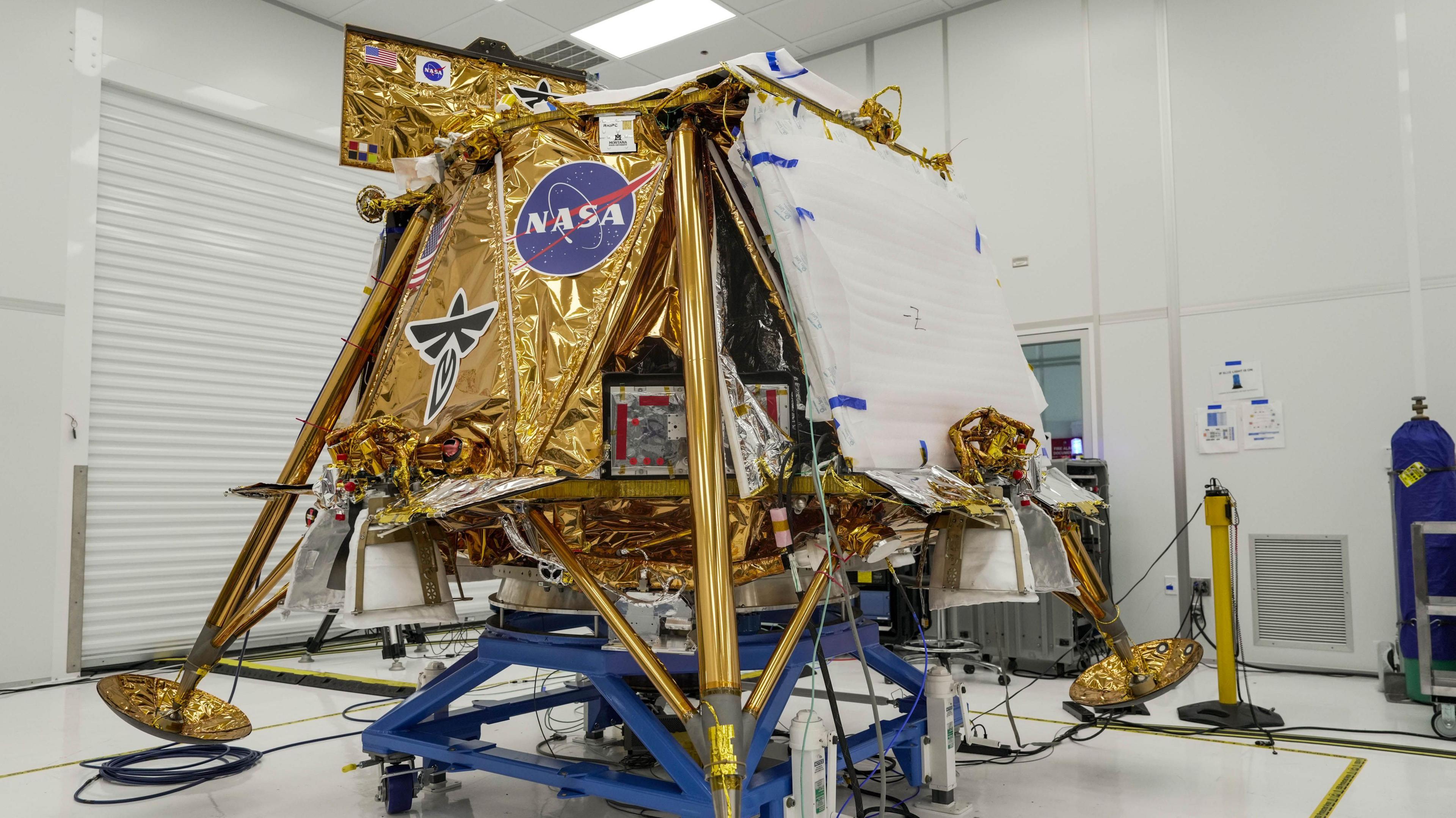 The Blue Ghost spacecraft photographed at Firefly Aerospace's headquarters in Texas. The square probe looks at least two metres tall and has legs protruding out at an angle. The body is covered in gold foil and has logos for Nasa and Firefly.