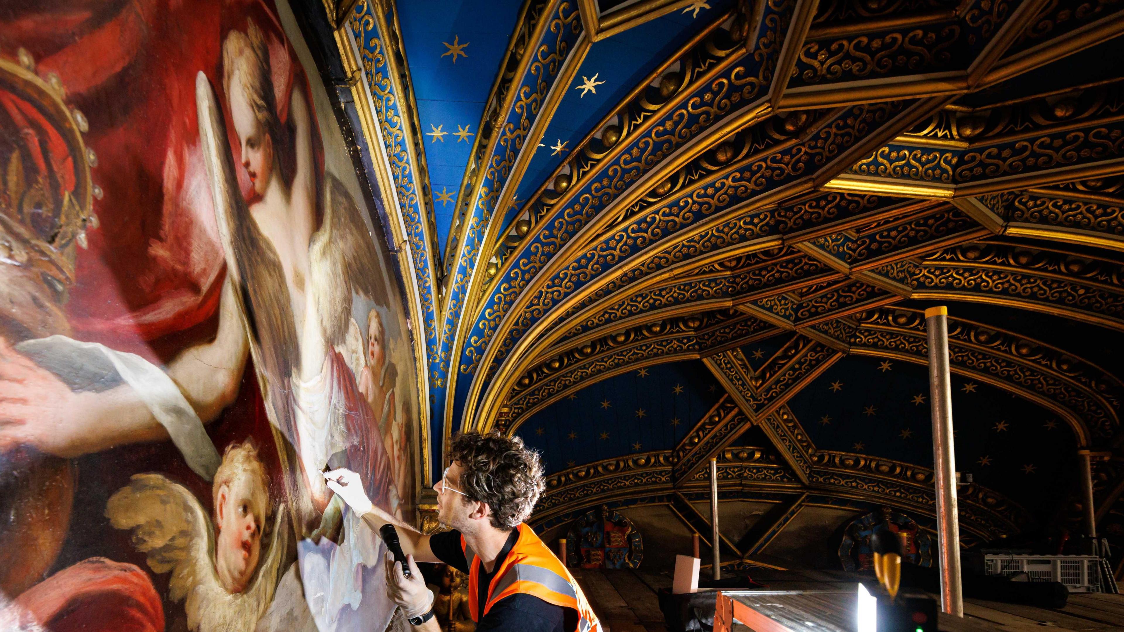 A curator works on a painting under the Chapel's vaulted ceiling 