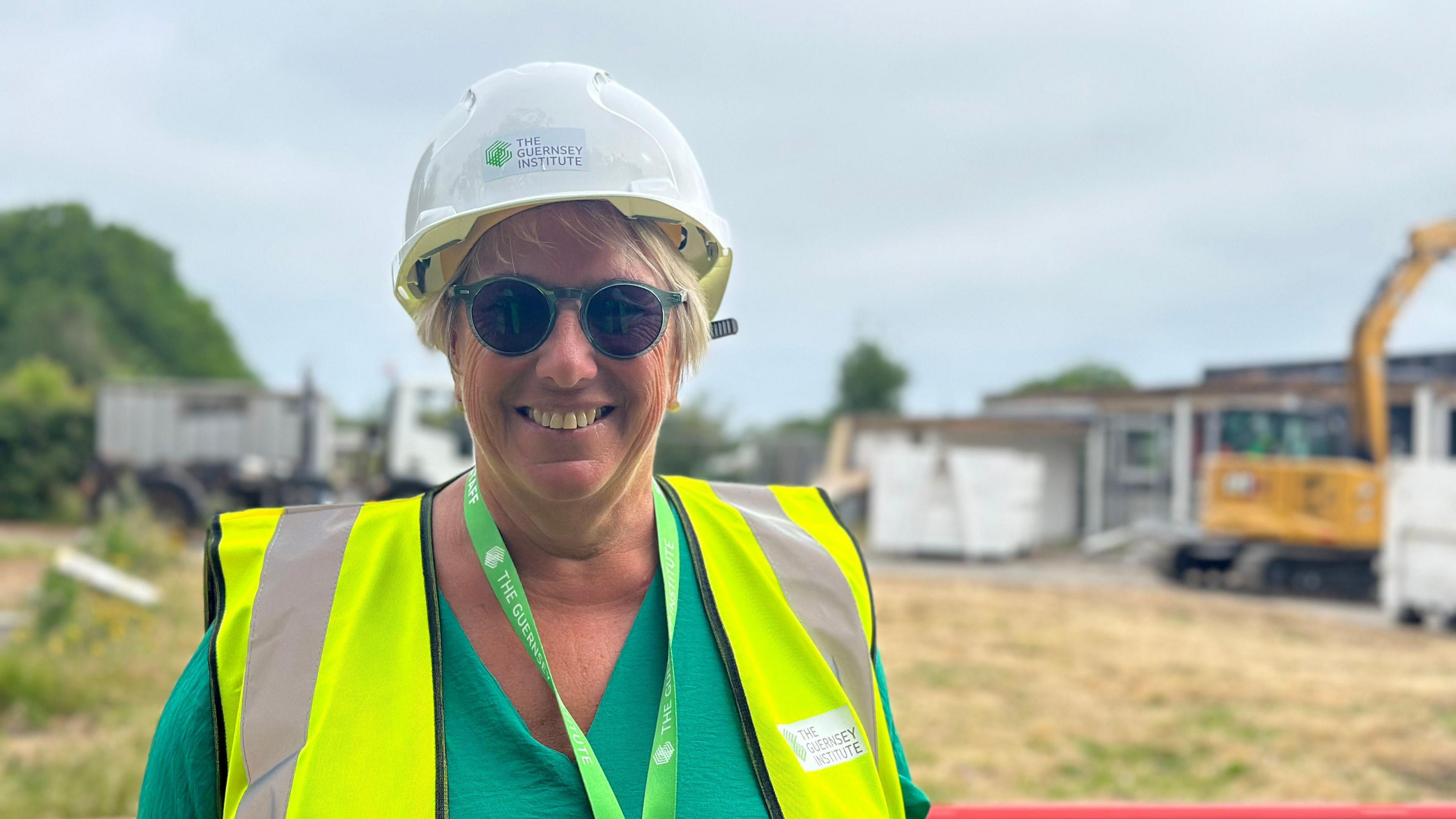 Guernsey Institute executive principal Jacki Hughes in a hard hat with demolition work in the background