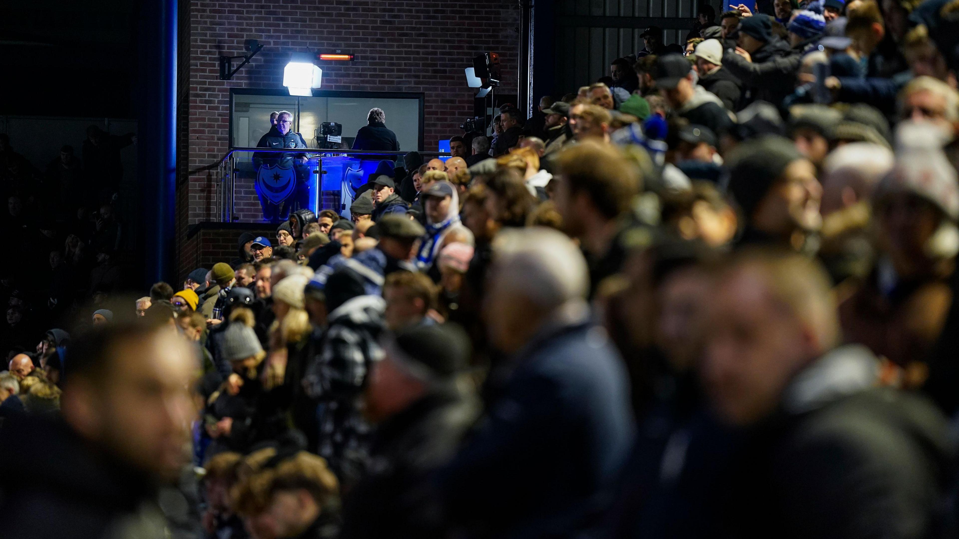 Portsmouth fans wait for news with the floodlights having gone out at Fratton Park