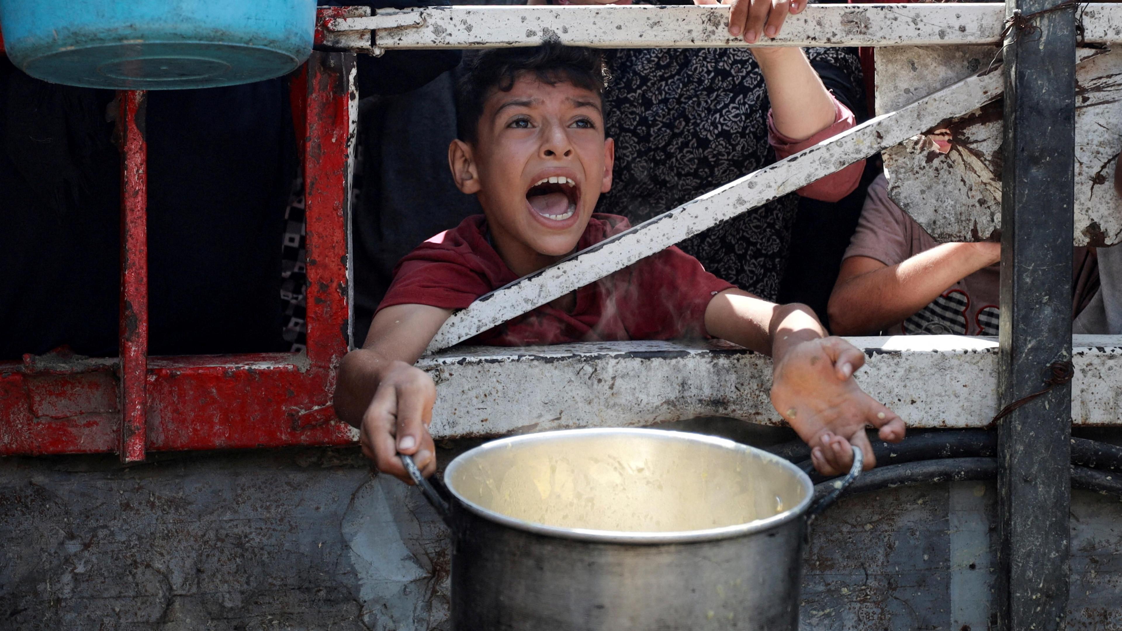A Palestinian child is caught mid shout, eyes full of anguish, as he waits to receive food from a charity kitchen, amid a hunger crisis in Gaza