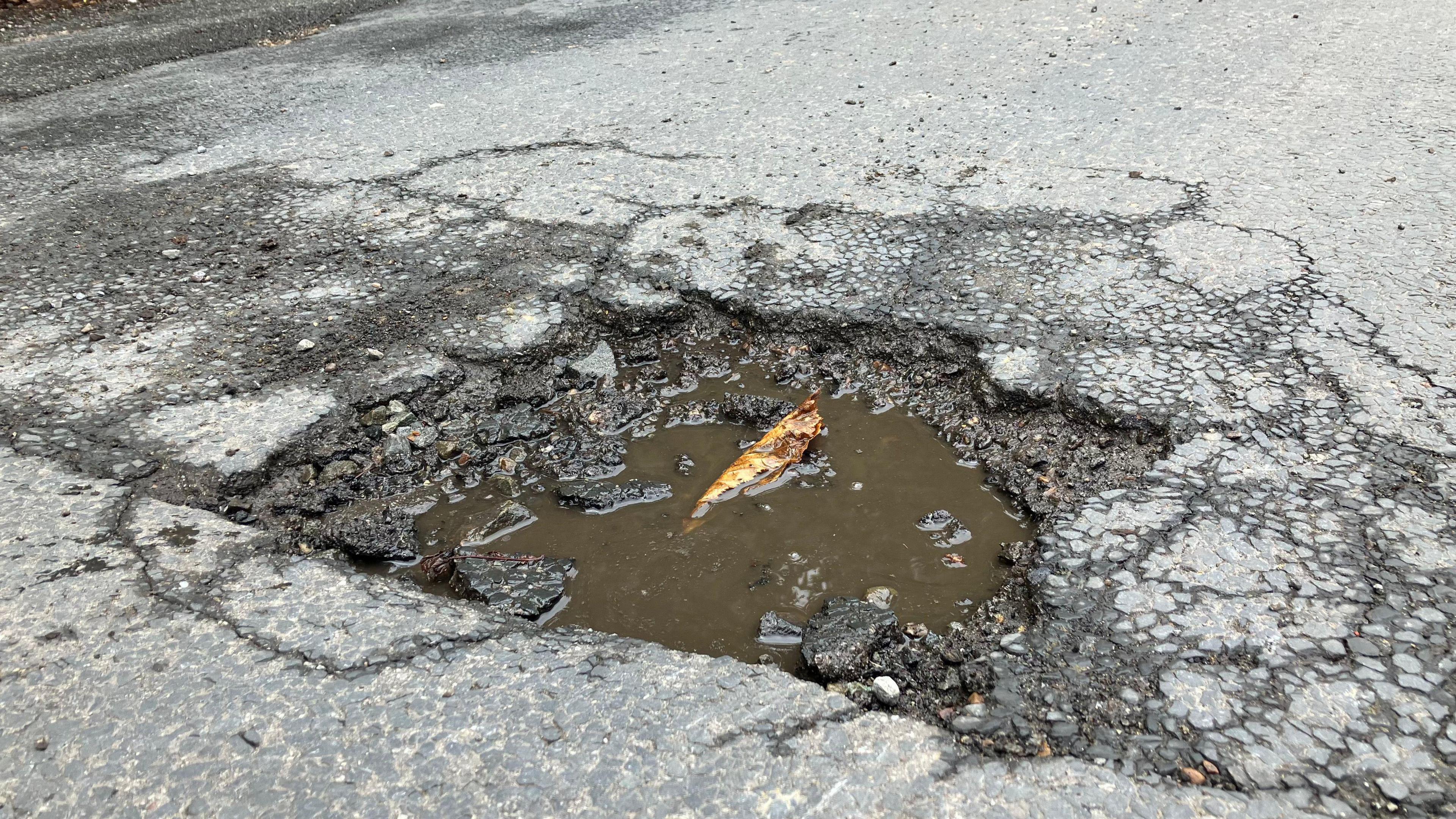 A pothole filled with muddy water