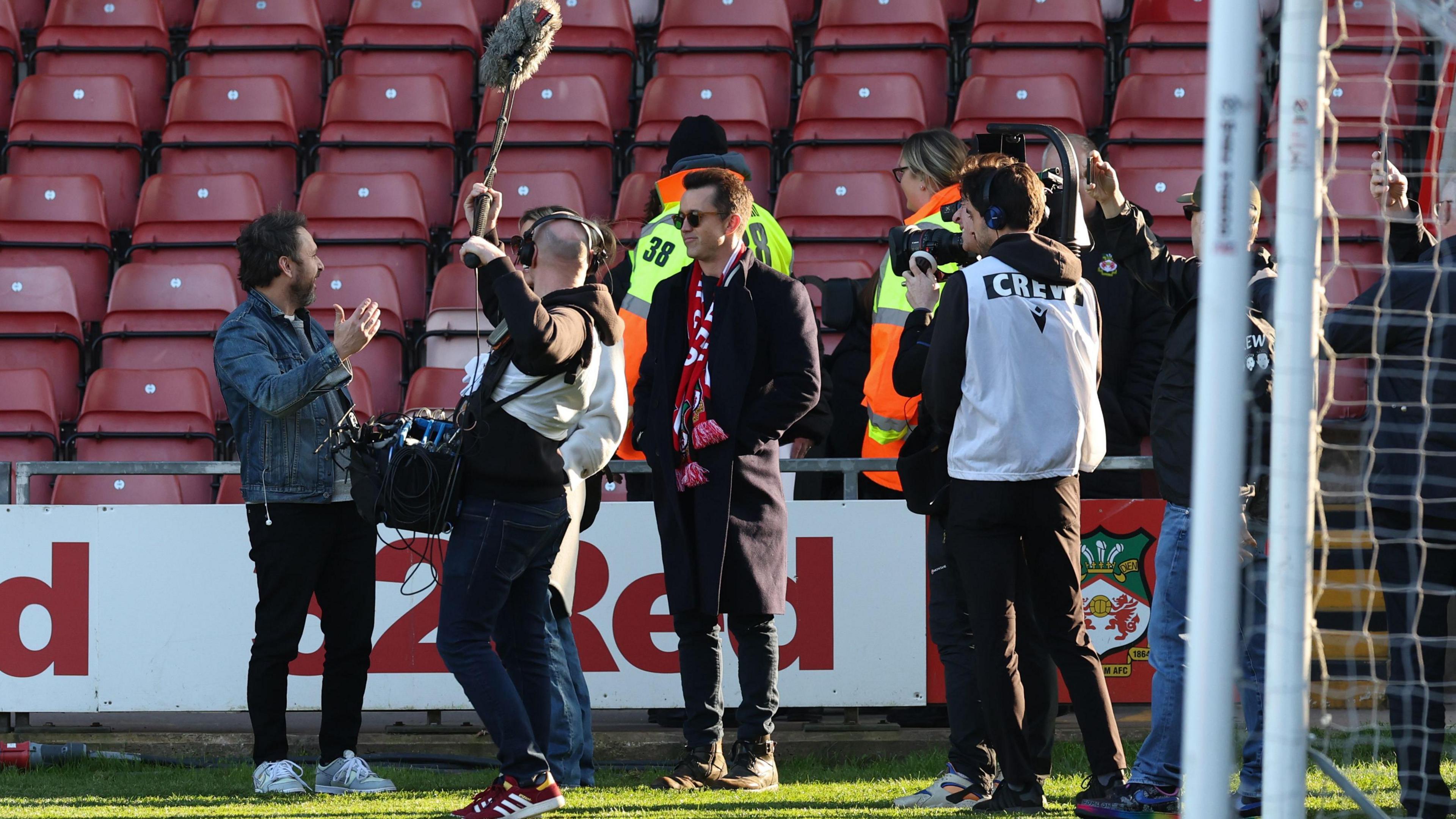 Wrexham co-owner Rob McElhenney pitch-side and surrounded by a film crew for the documentary Welcome to Wrexham 