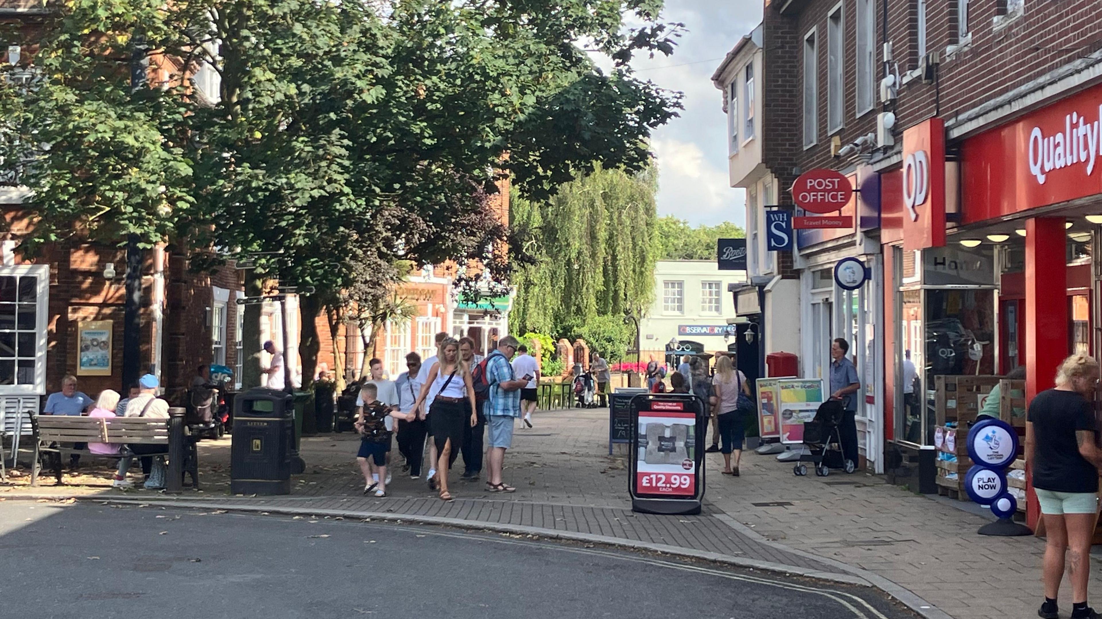 Beccles town centre showing large tree, post office and people walking in the dappled sunshine