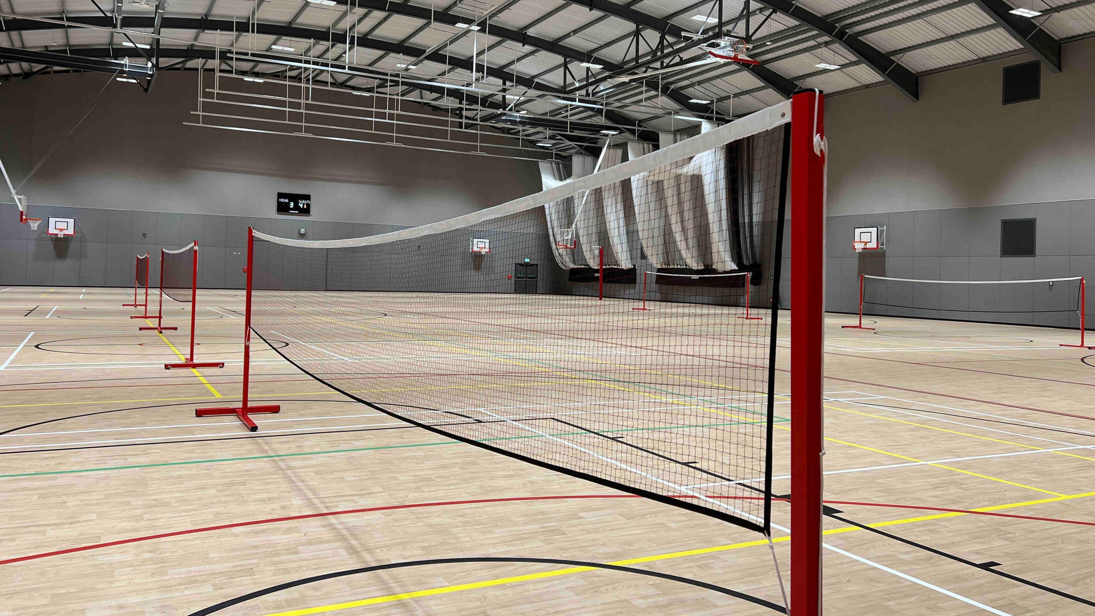 A new indoor sports pitch has different coloured lines on the floor and nets positioned across the hall.