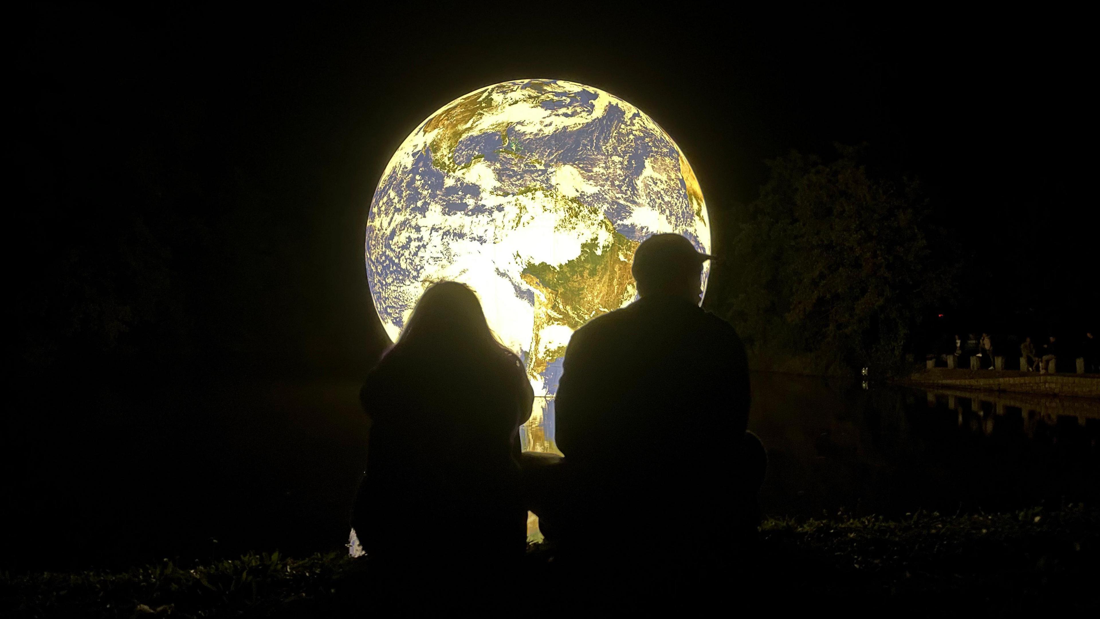 People looking at Floating Earth on reservoir in Jersey