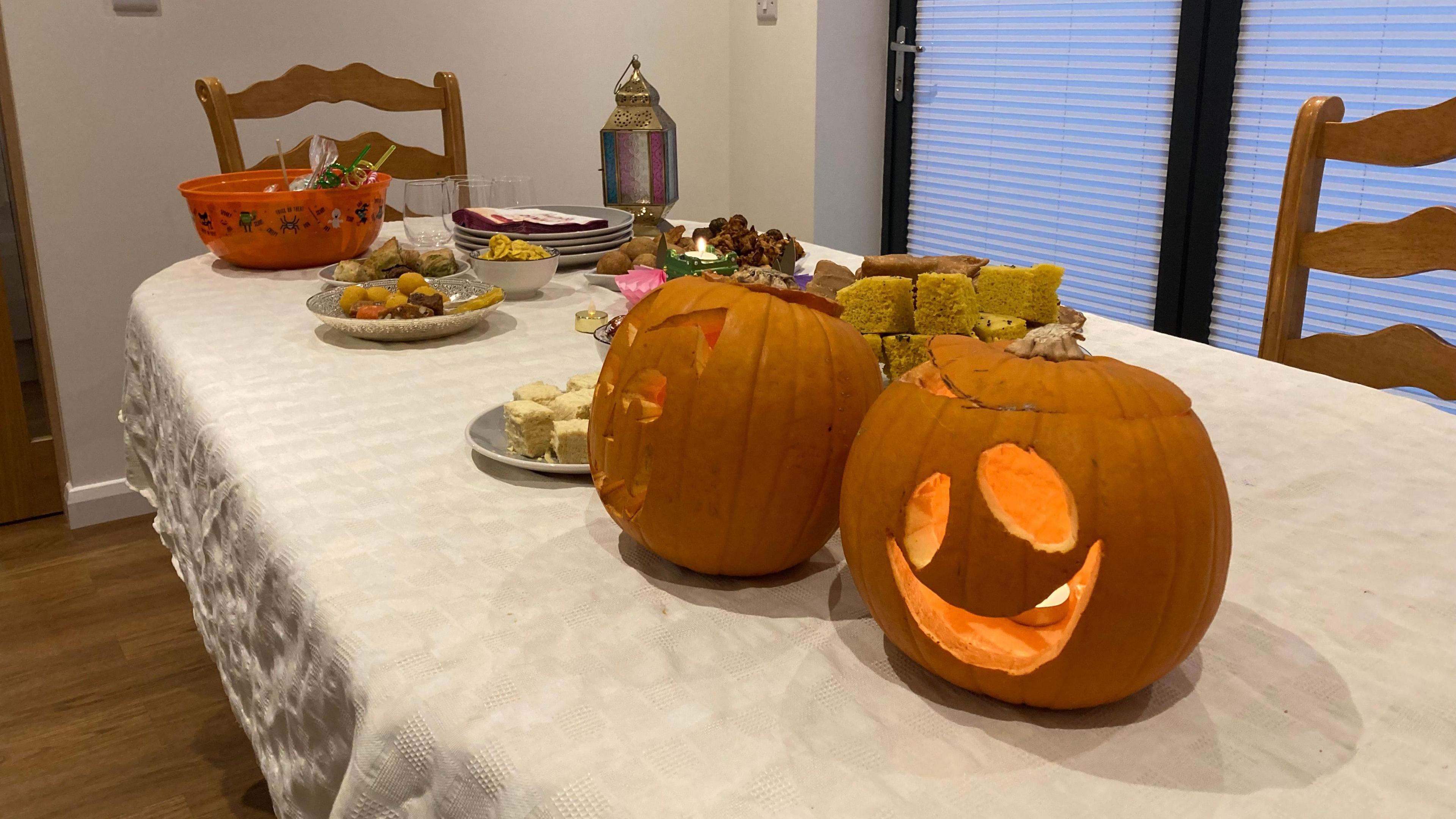 Calved pumpkins on a dining room table with a buffet behind