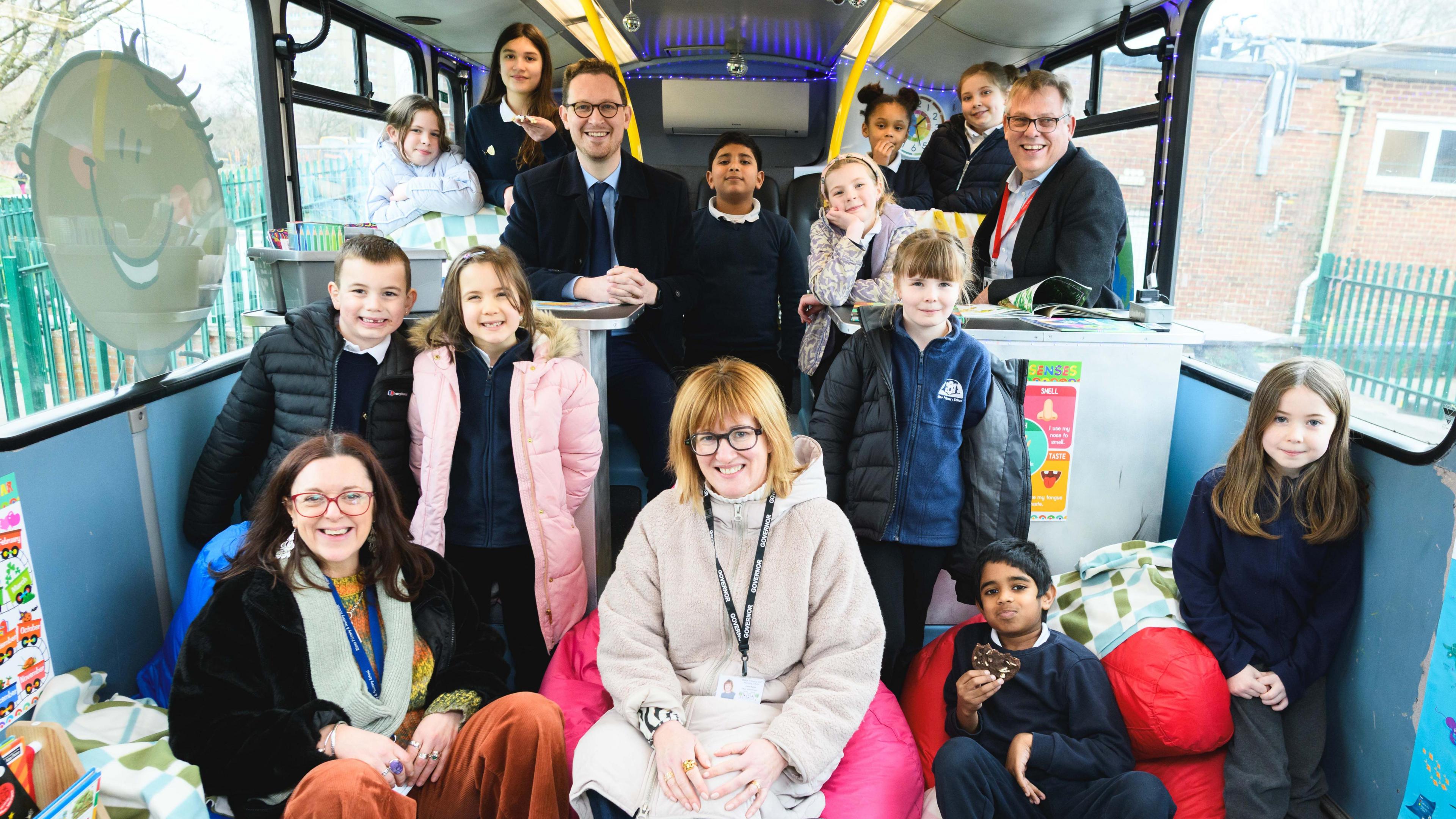 Pupils and adults gathered on the lower floor of the bus, smiling at the camera