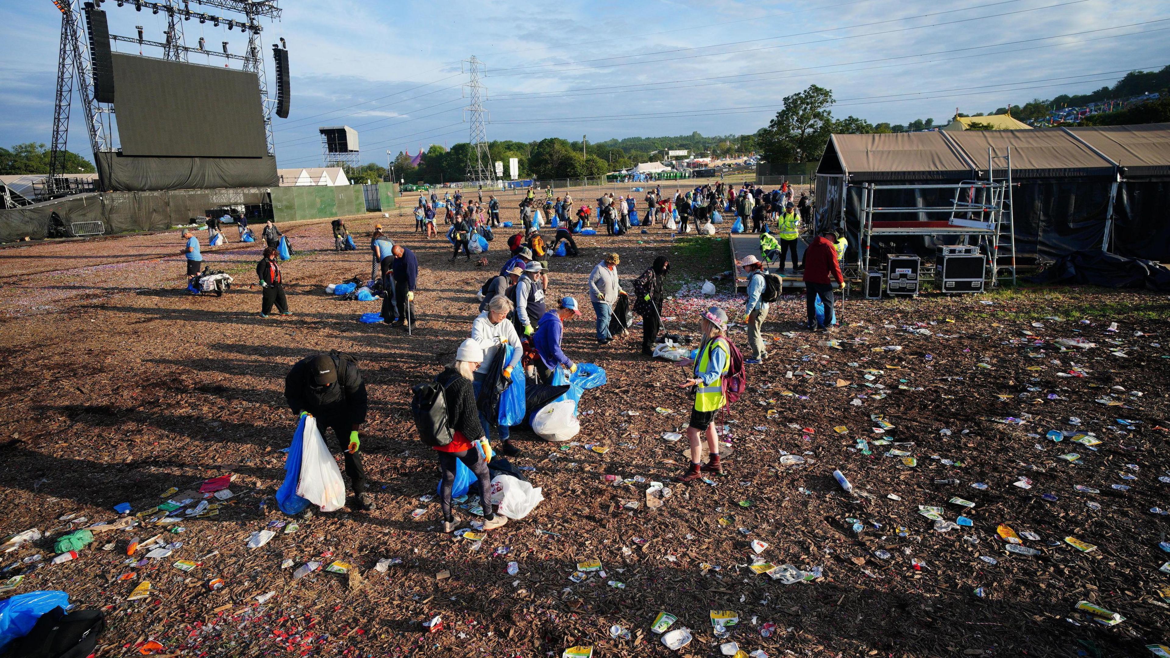 People cleaning in front of the Pyramid Stage with litter all across the ground