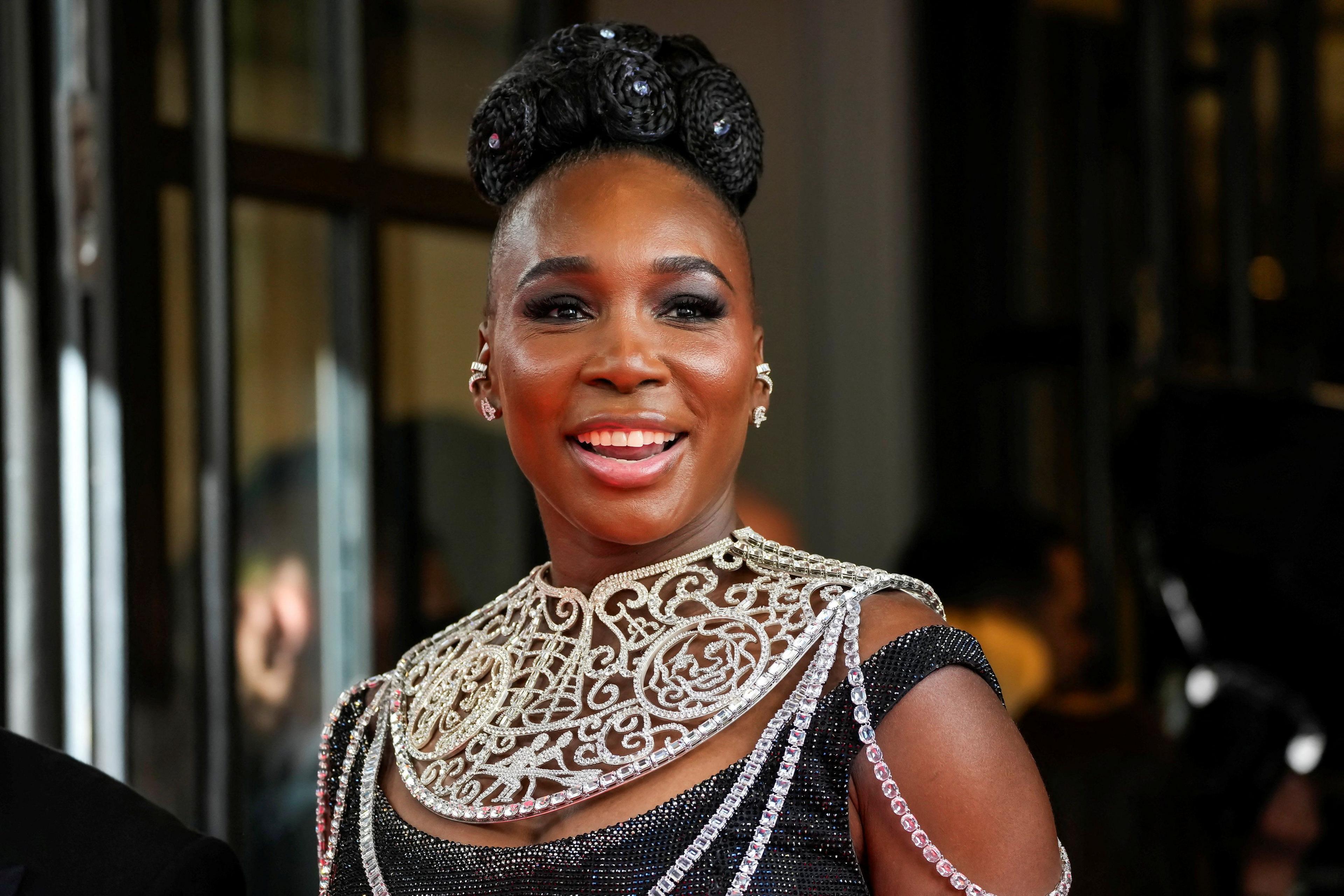 Venus Williams departs Mark Hotel, during the Met Gala. She has her hair in a large bun on top of her head, anc is wearing a black dress with a ornate necklace. 