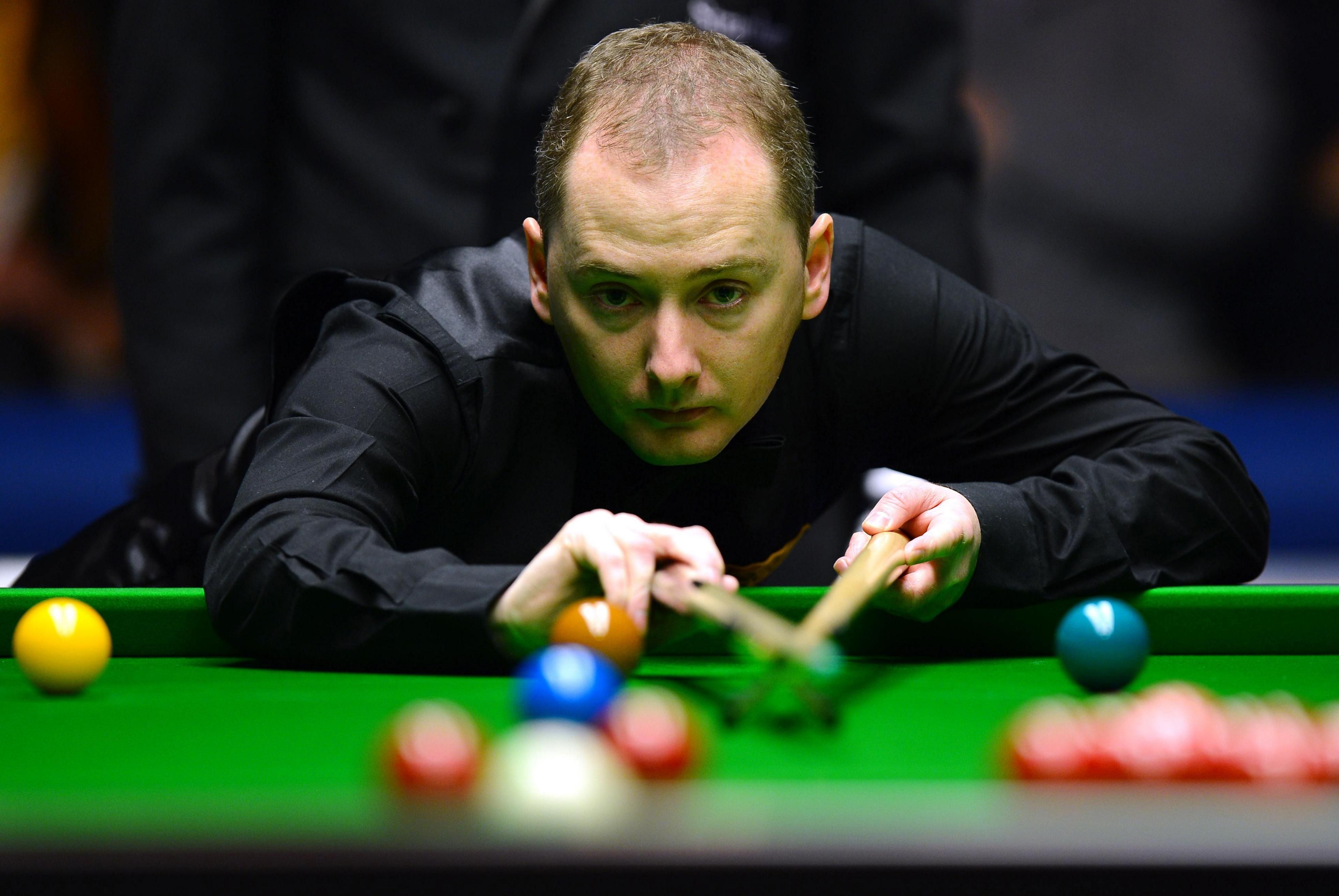 Graeme Dott lines up a shot across a snooker table, with coloured balls in the foreground.