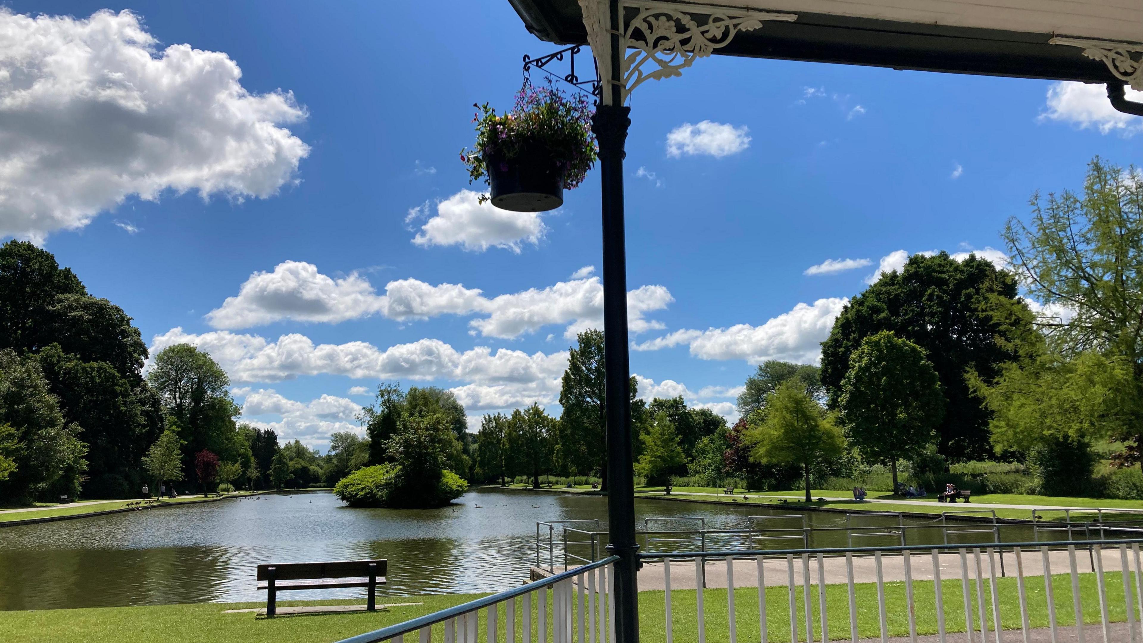 A view looking through the bandstand to the lake under a blue sky