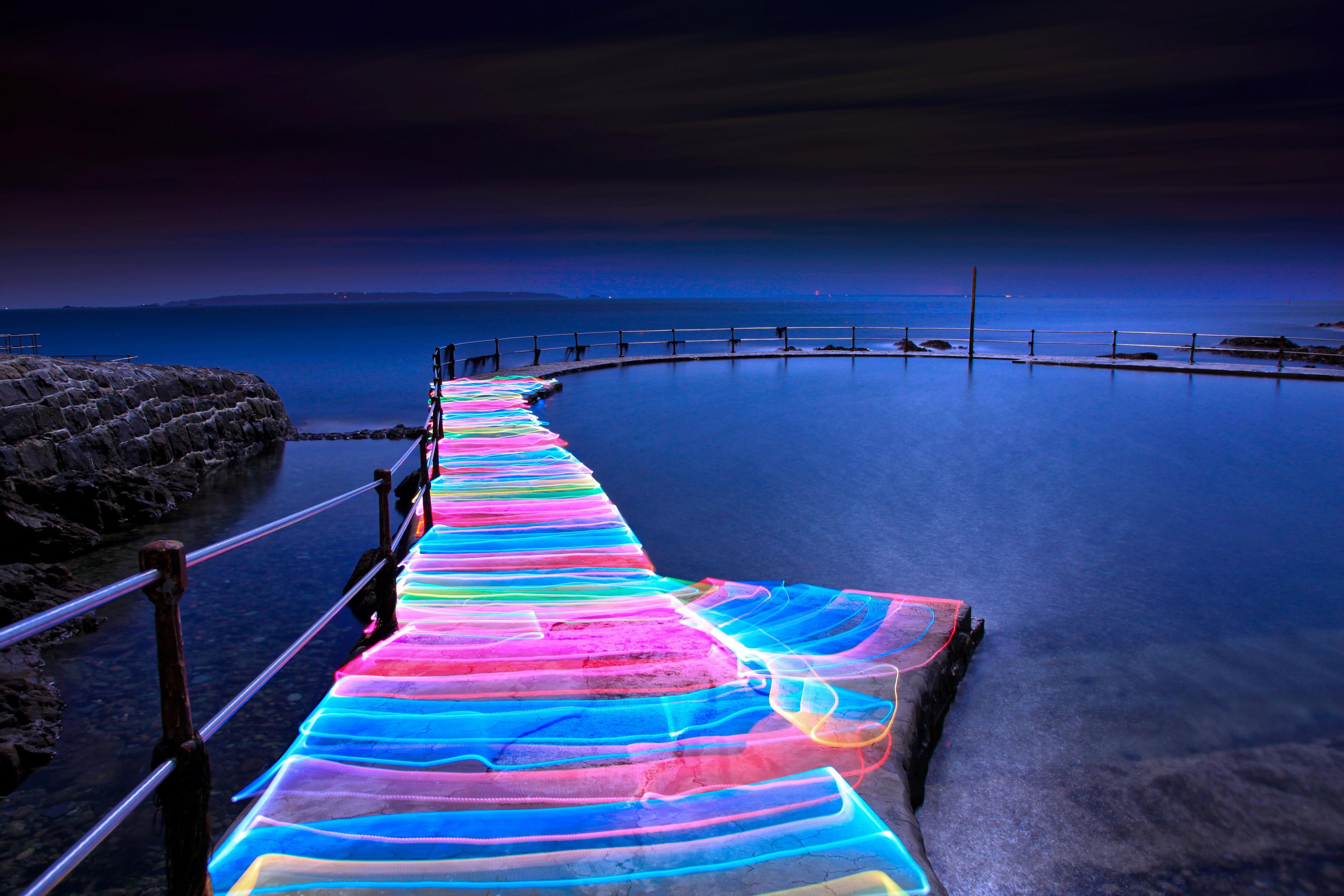 A stone walkway covered in rainbow light next to the Loch Lomond. 