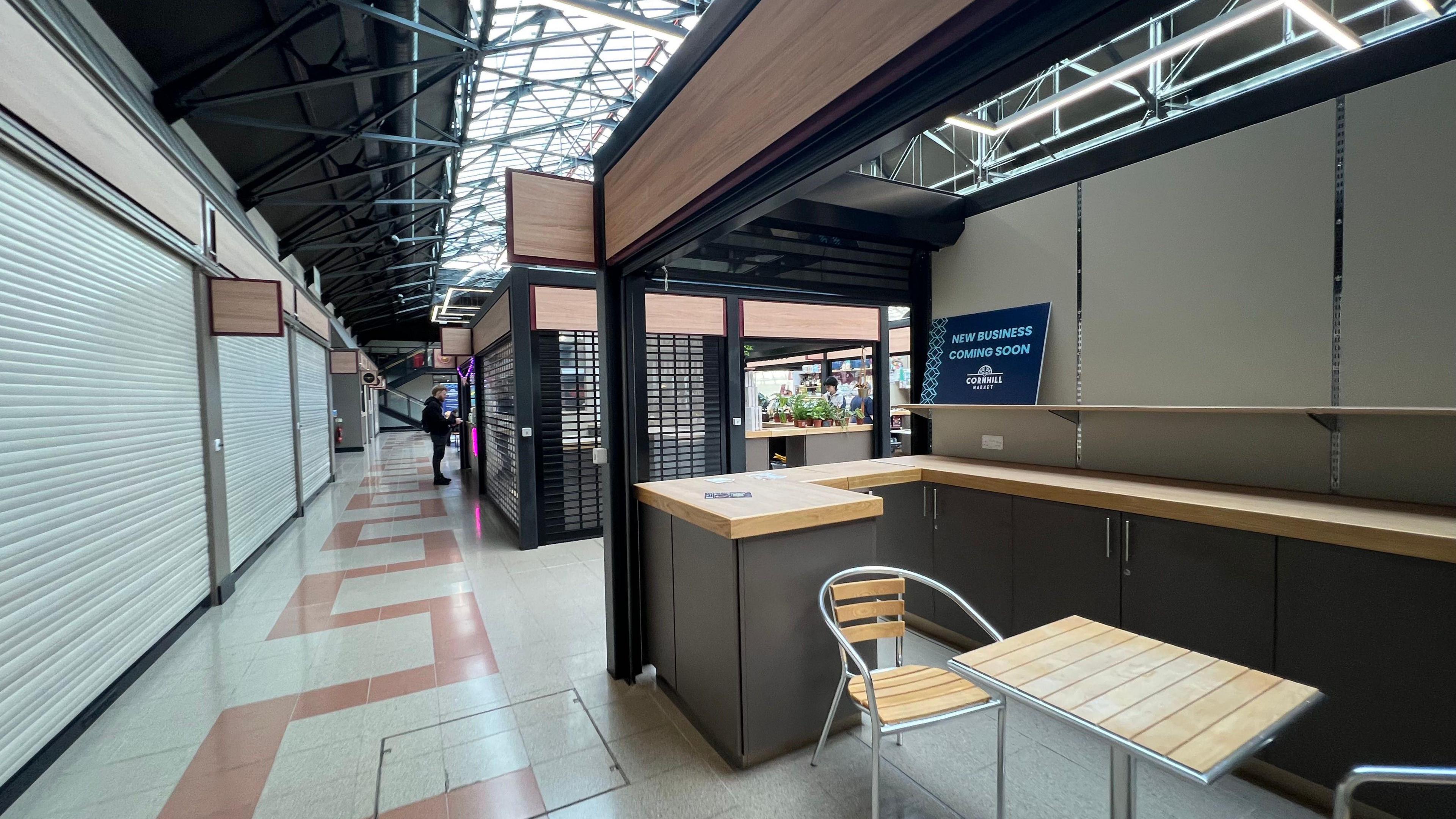 Empty stalls with shutters down at an indoor market. 