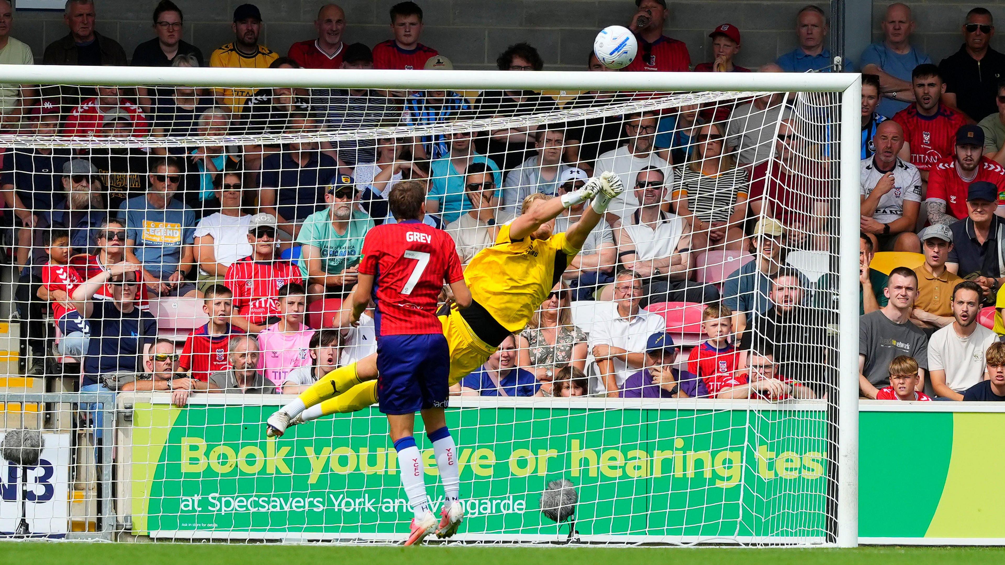 The Bristol Rovers goalkeeper dives high to the right to push the ball over the bar from a York City player.