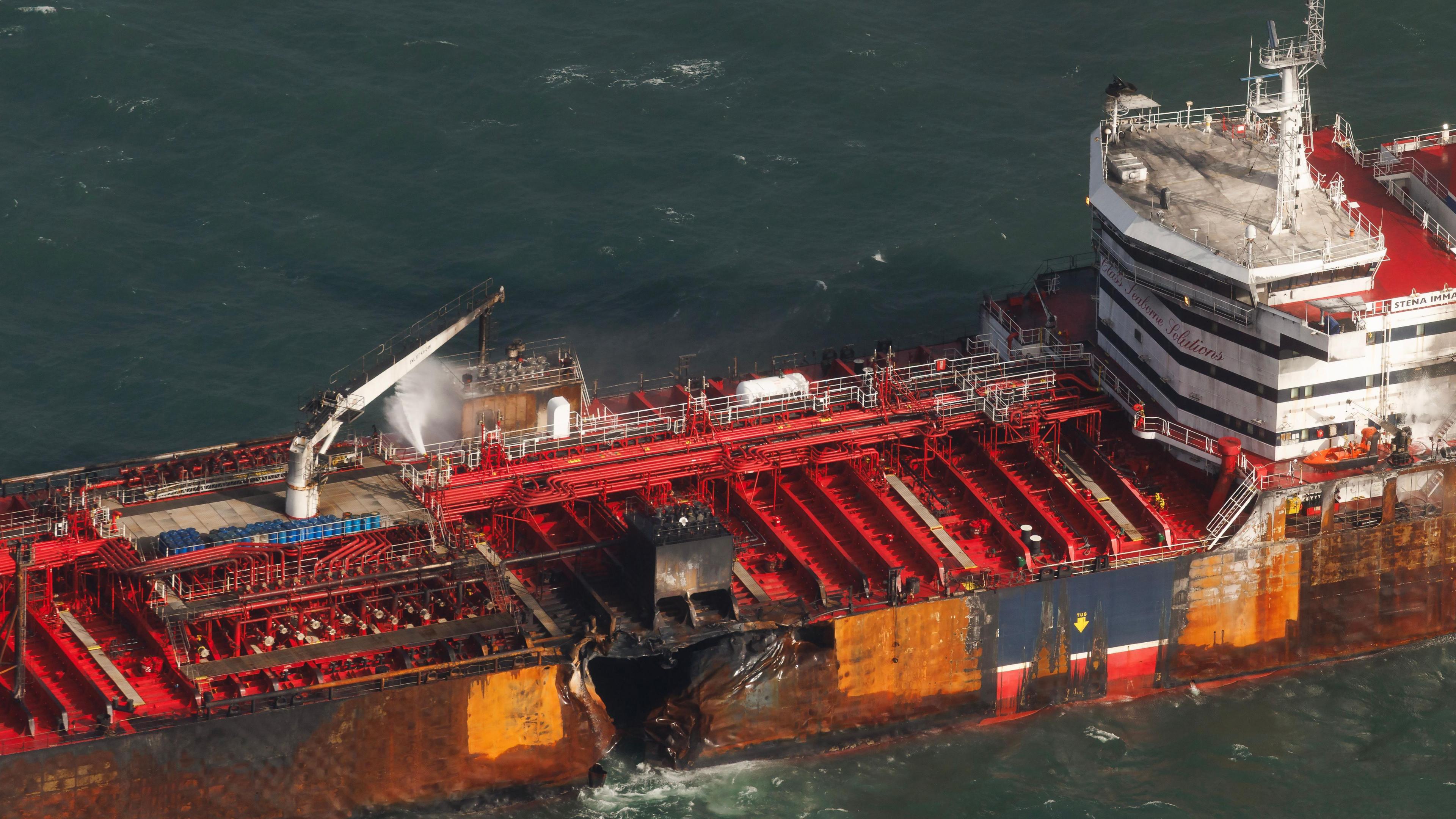 The damaged oil tanker at anchor off the Yorkshire coast in the North Sea. A hole in the middle of the boat is visible, with water gushing out.