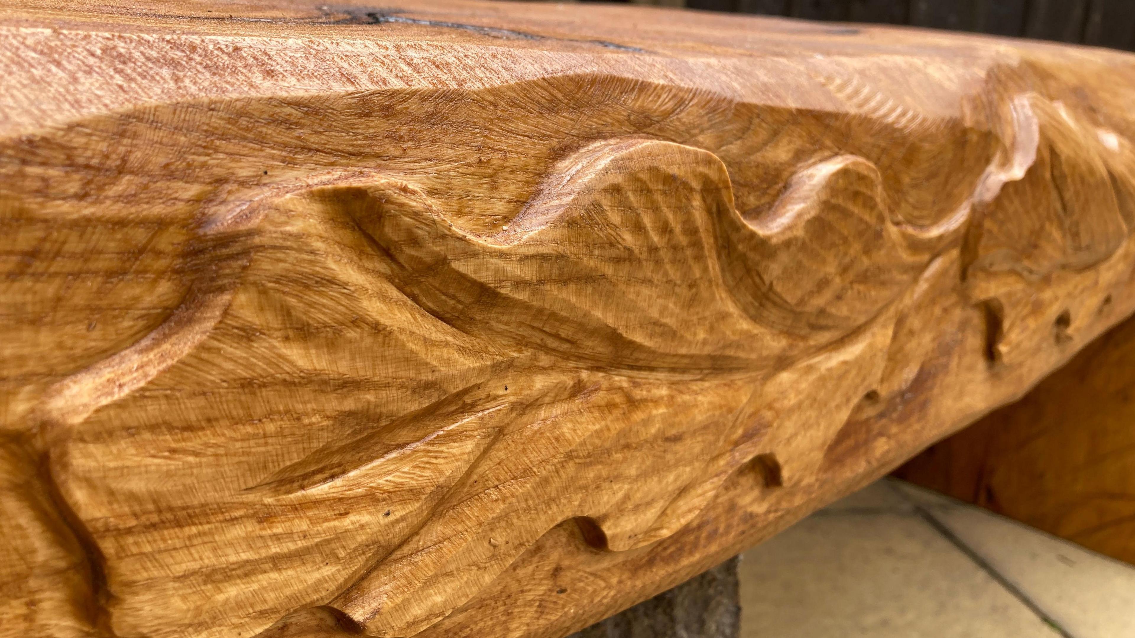 A wooden bench with oak leaves carved into it.