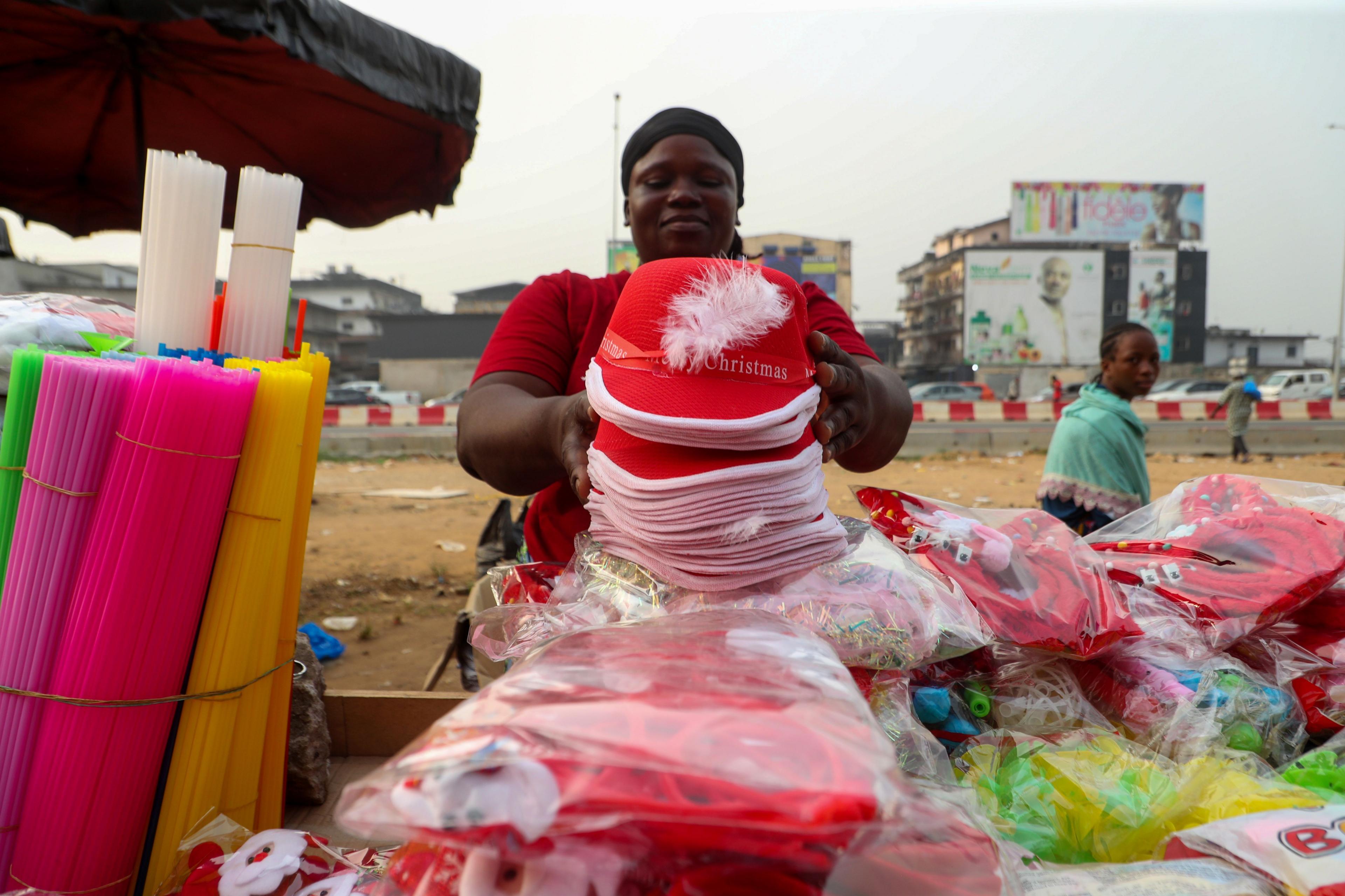 A vendor sets Christmas and New Year's decorations for display at her roadside stall in Abidjan, Ivory Coast - Thursday 19 December 2024.