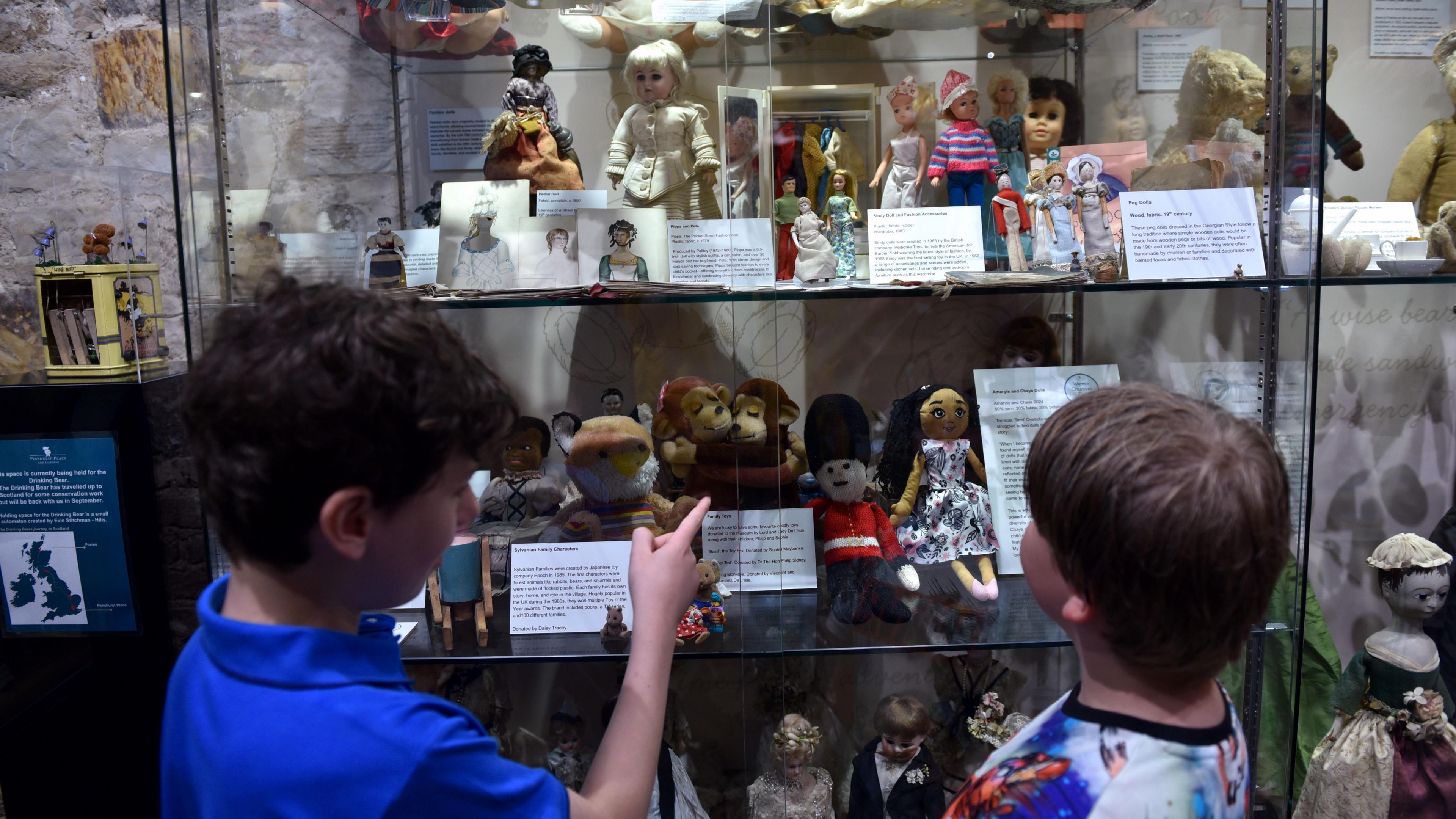 Two children looking at a variety of toys from different eras displayed at museum in Kent.