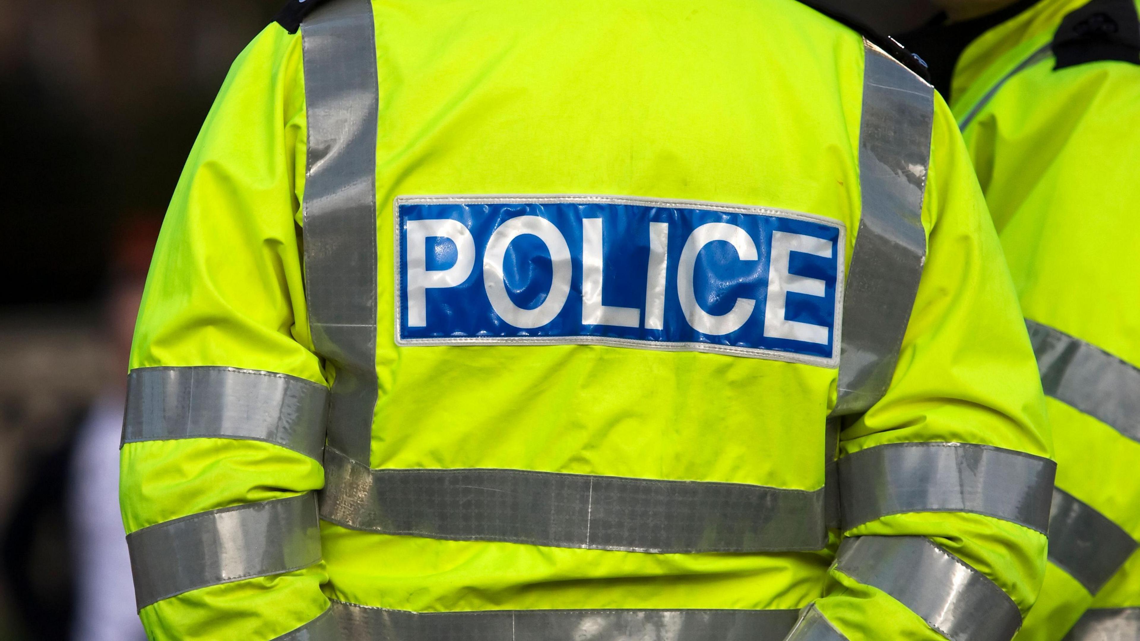 Back view of a police officer in reflective jacket - stock photo