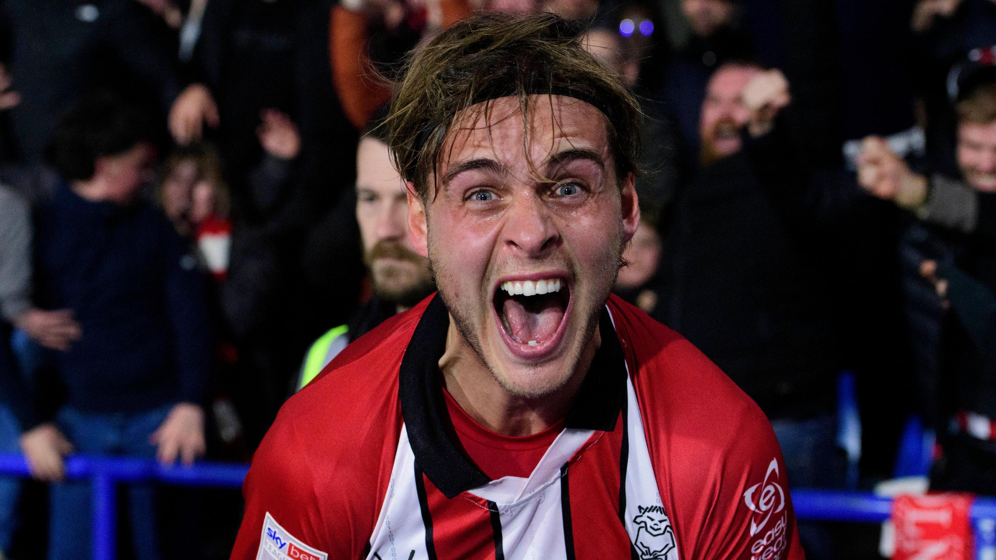 Ryley Towler celebrates scoring his equaliser for Lincoln at Hudderfield in front of the Imps' fans