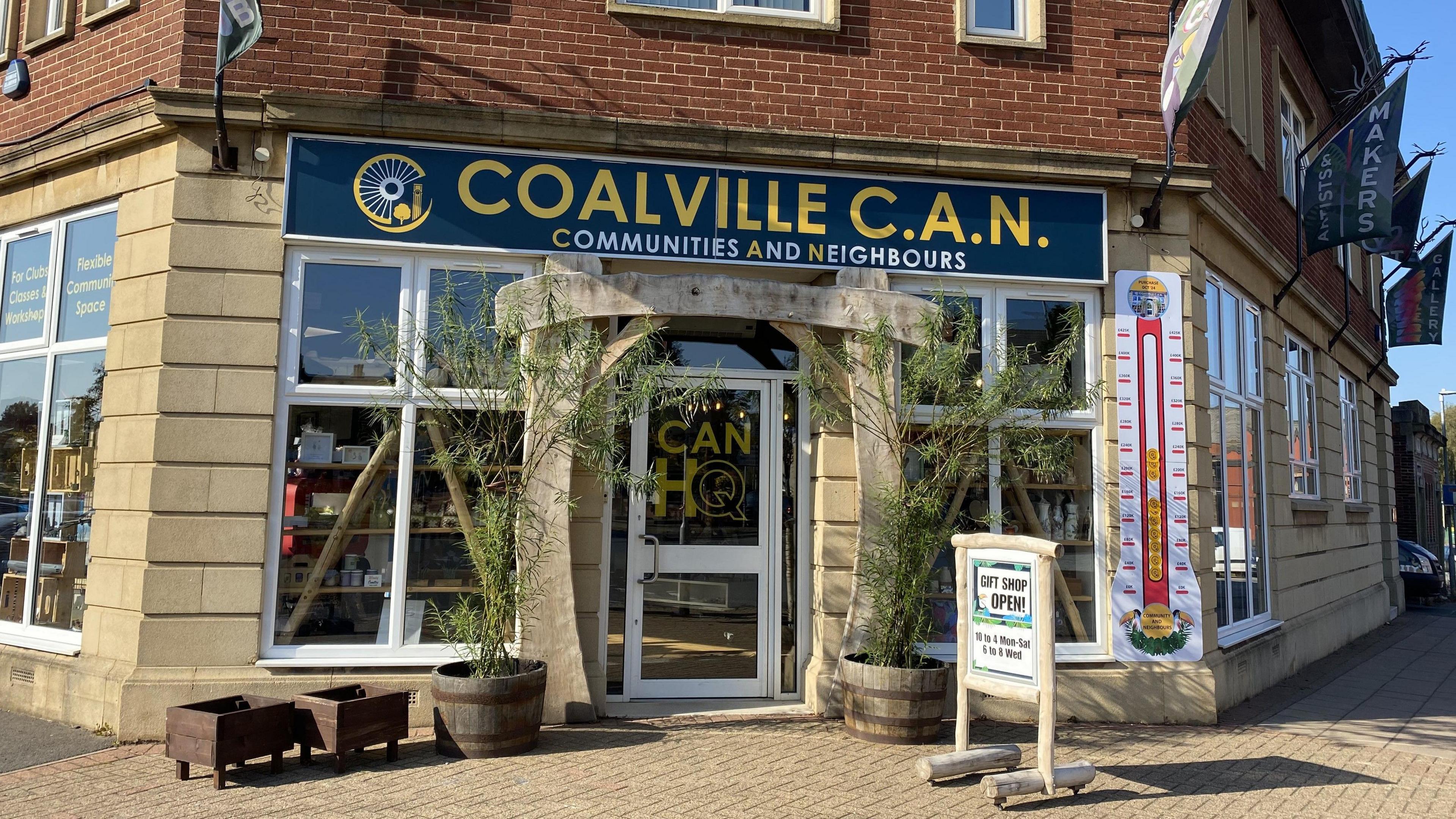 The exterior of Coalville CAN with pot plants and an advertising board