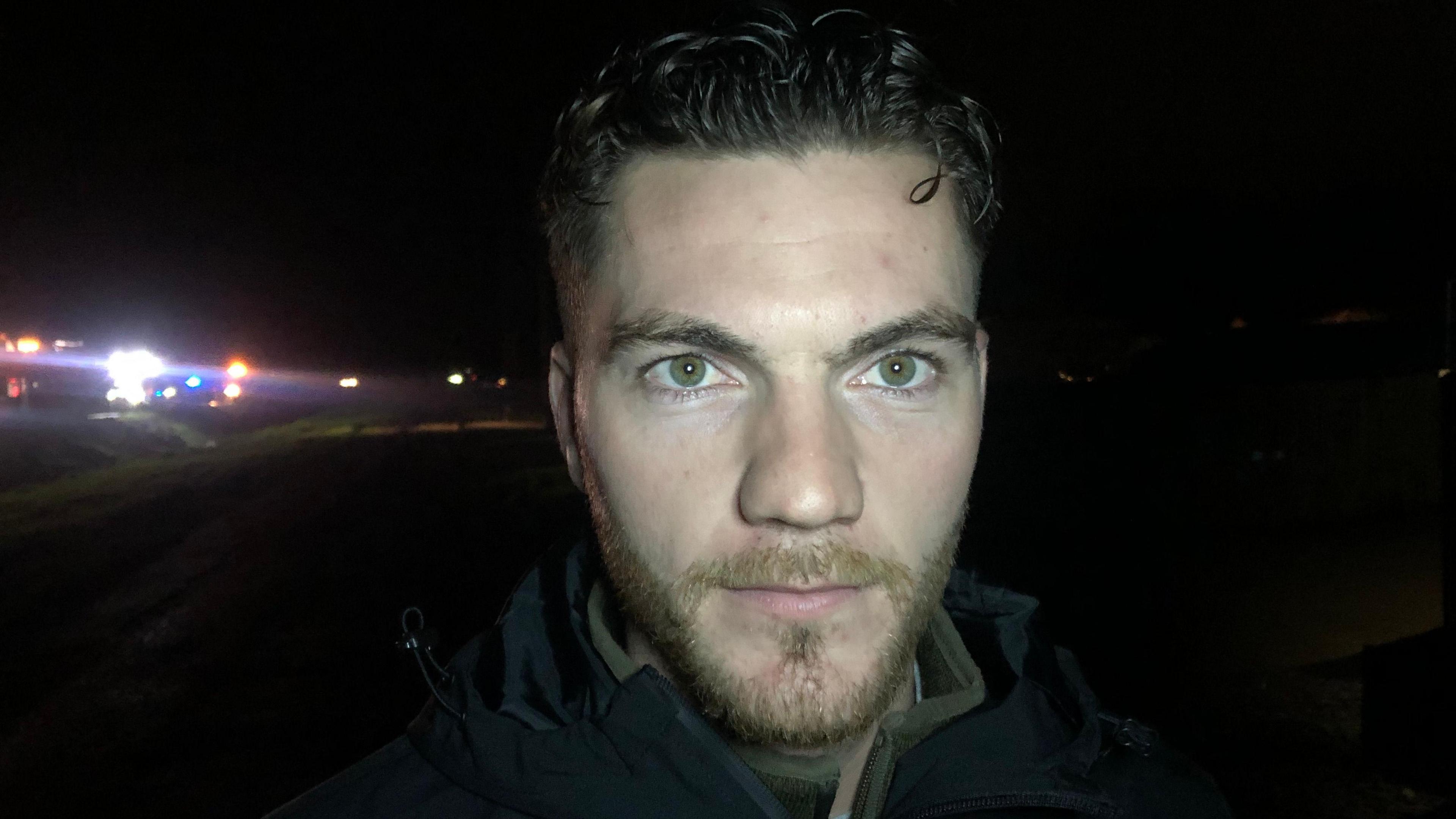 Laurence Manning, a man with a beard and brown hair. He is wearing a black fleece. He is stood outside in the dark near the scene.