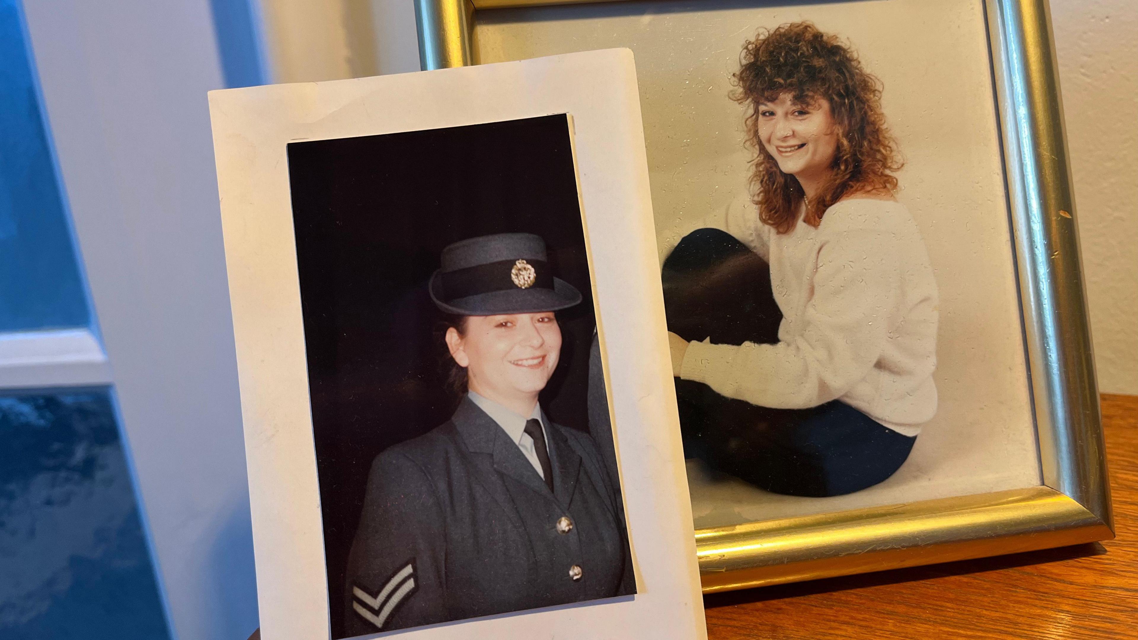 Two pictures in frames, one of a woman in an RAF service uniform, the other photo is of the same woman in a white jumper and black trousers sat on the floor