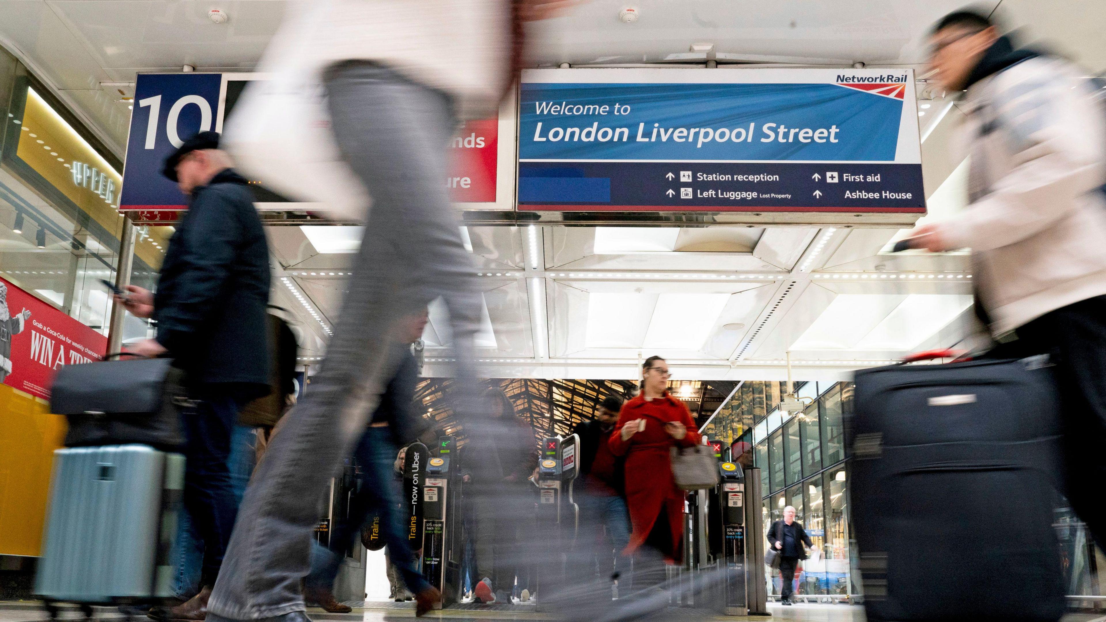 A group of people near a set of ticket barriers in a concourse.