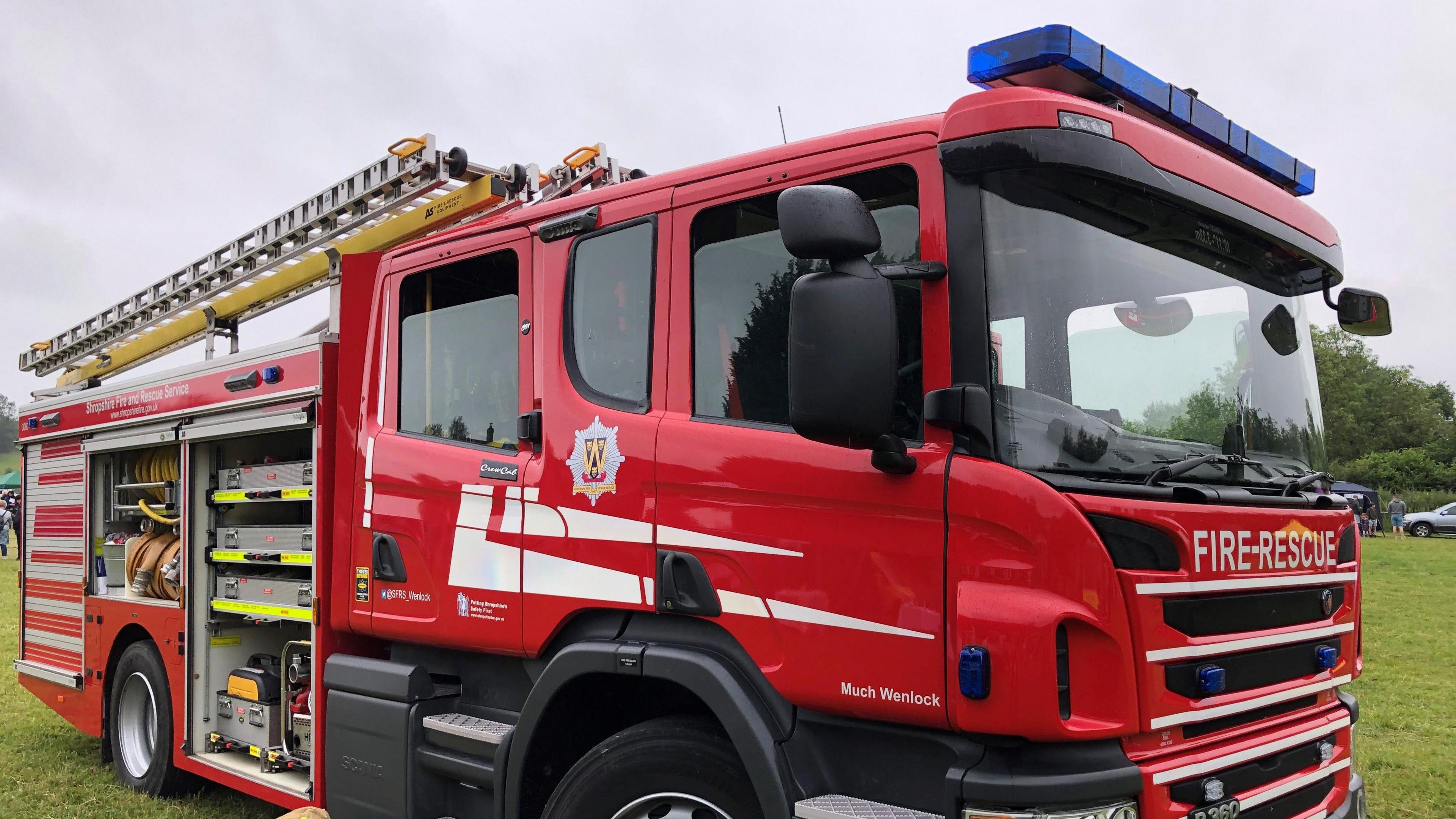 The side of a red fire engine parked on grass