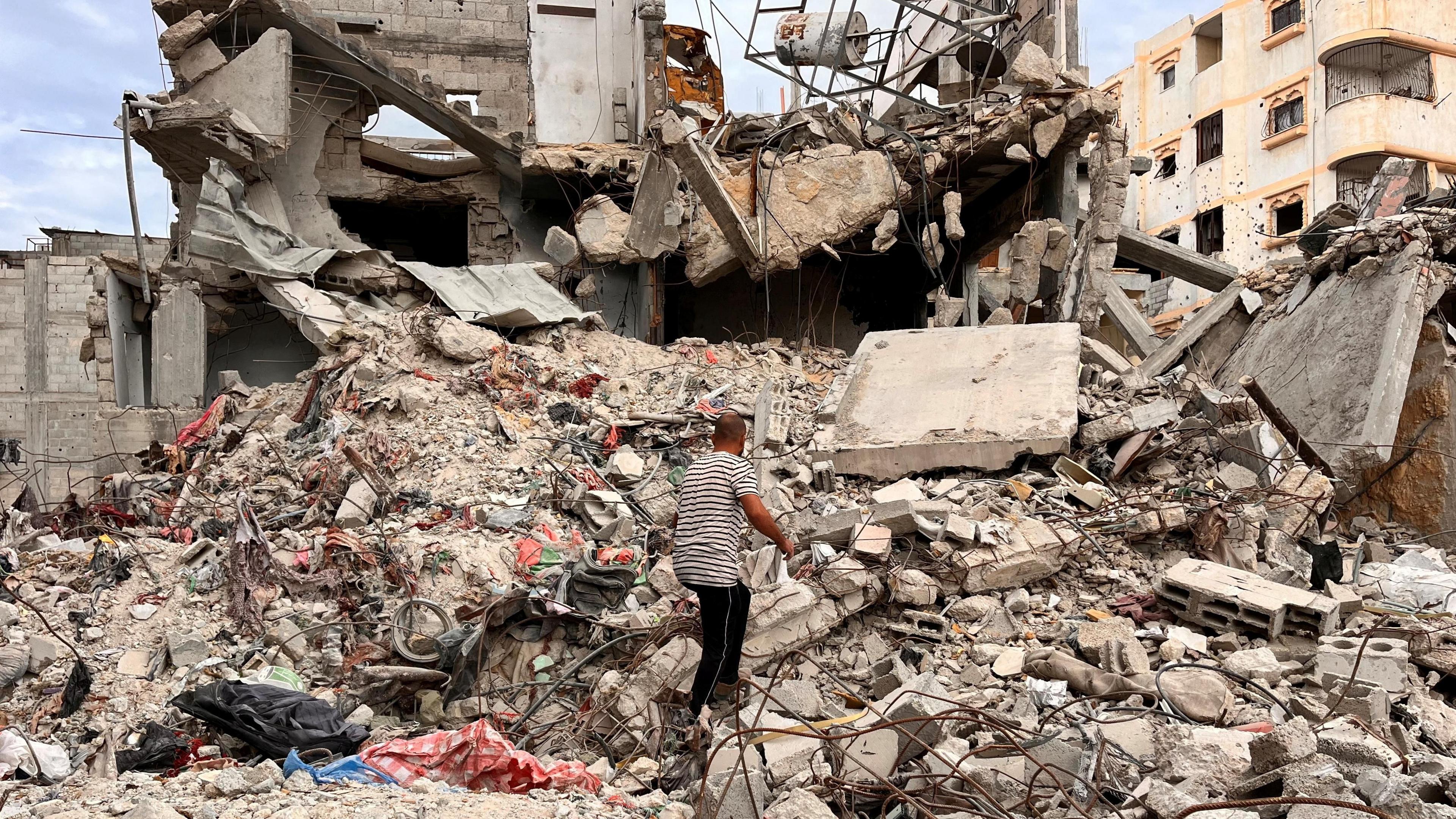 A Palestinian man searches for clothes in the rubble of a house destroyed in an Israeli air strike in Khan Younis, in southern Gaza (18 November 2024)