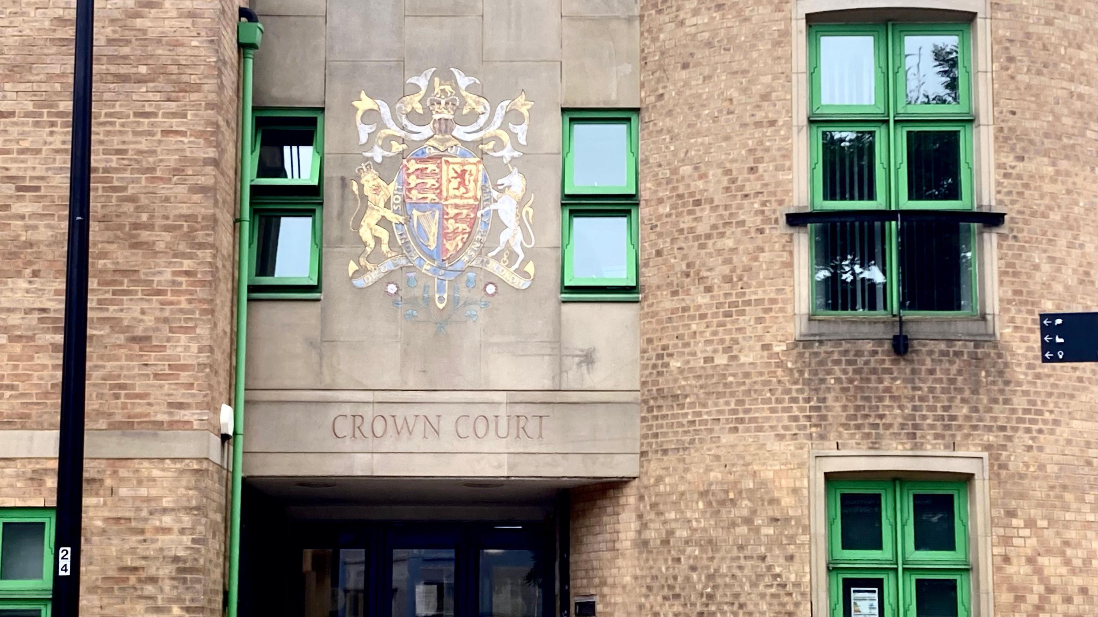 The outside of a court building. A crest and words "Crown Court" are engraved on the side of the building. 