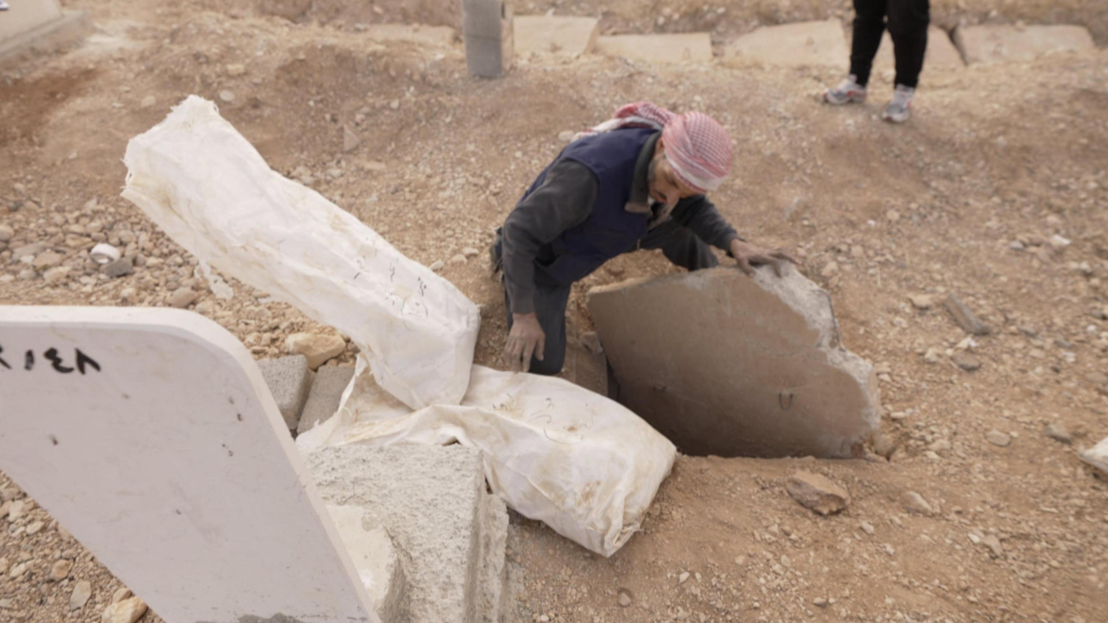 A man searching through graves in Syria 