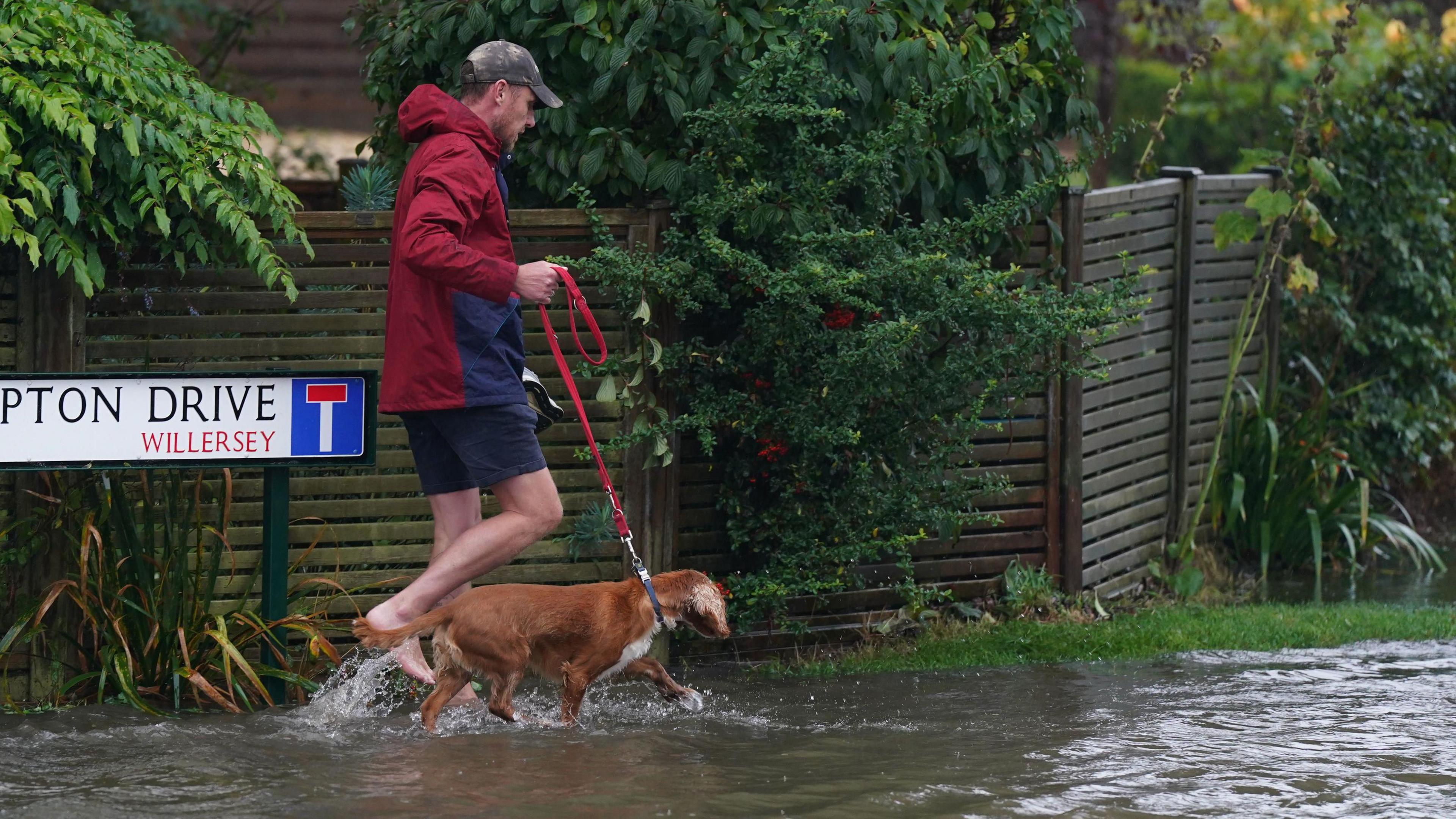 Man walking in floodwater with a dog in Gloucestershire