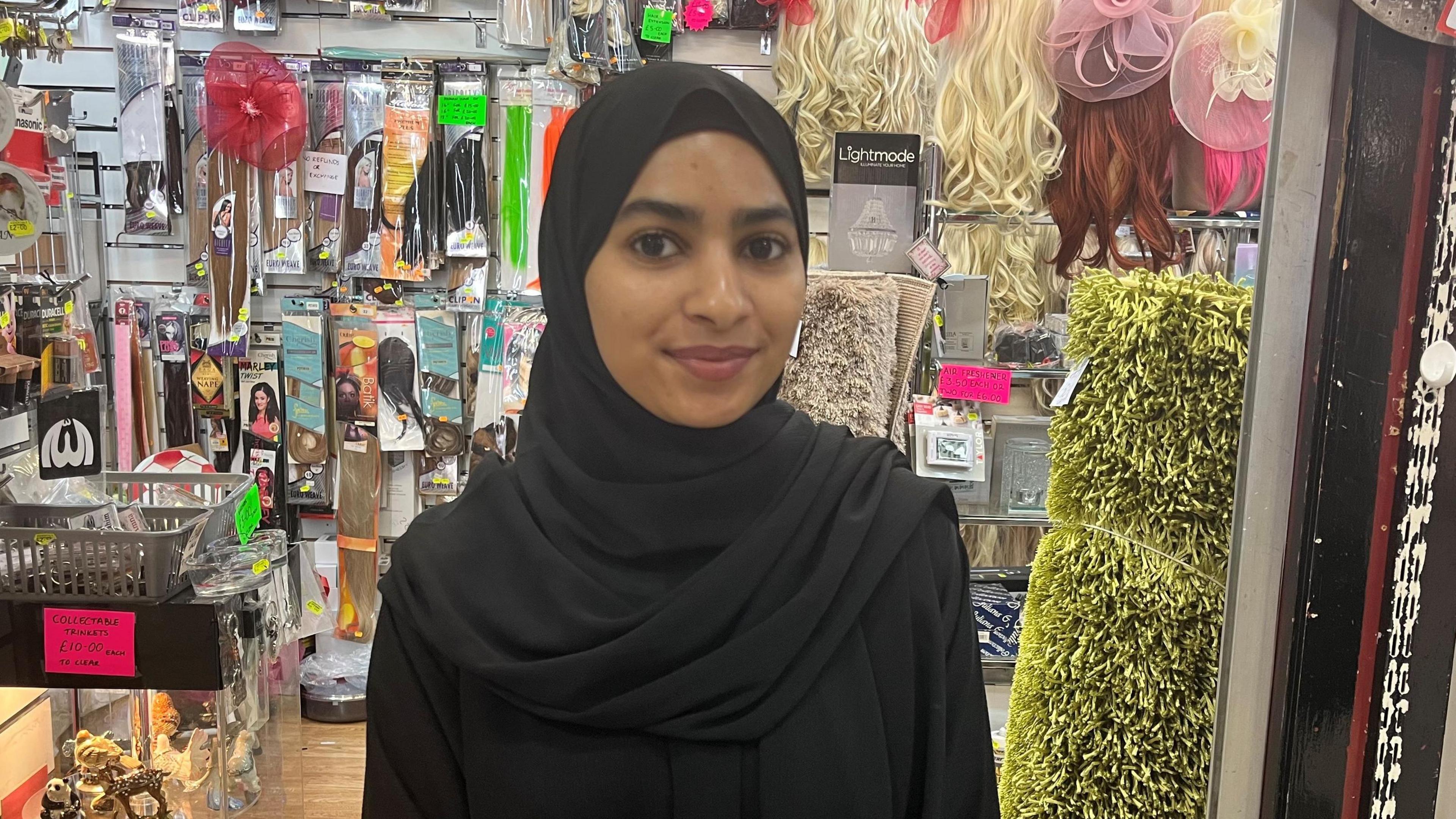 A young woman wearing a hijab in front of a store