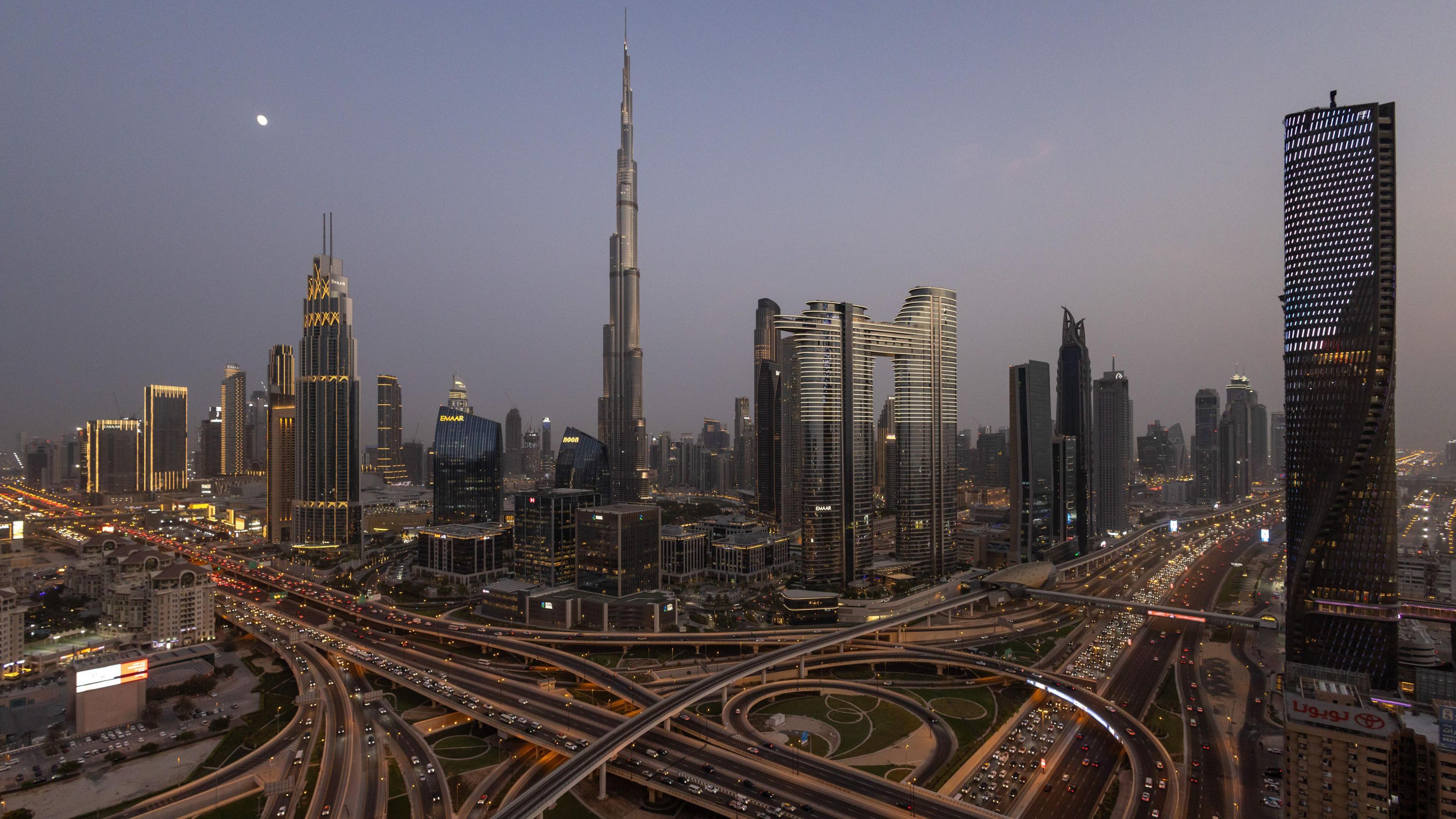 Wide shot of the Dubai skyline, taken at night. It features a number of striking, illuminated buildings, including the 828 metre (2,717 ft) Burj Khalifa, which has been the world's tallest building since 2009.