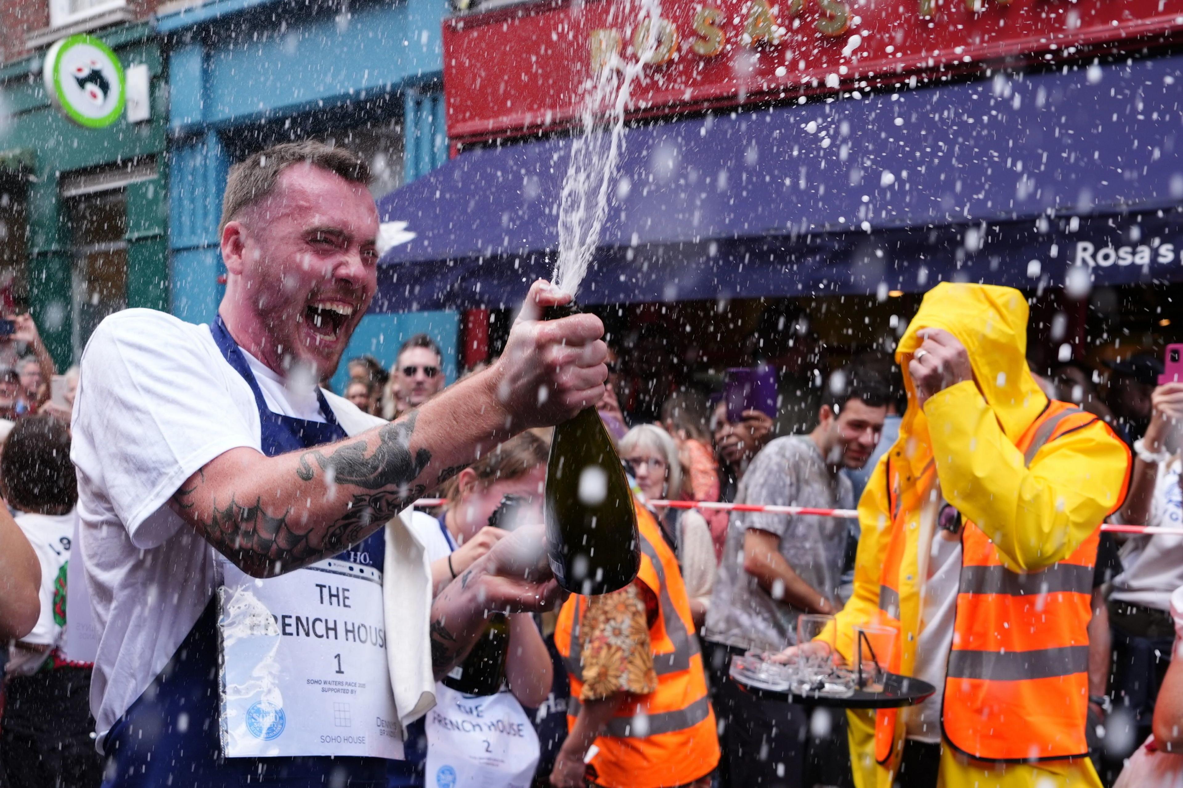 People celebrate after participating in the Soho Waiter's Race at the 50th Soho Village Fete in central London. Soho's waiters, hospitality and bar staff race their way through the streets of Soho in a bid to win a trophy and £100 cash prize. Picture date: Sunday July 20, 2025