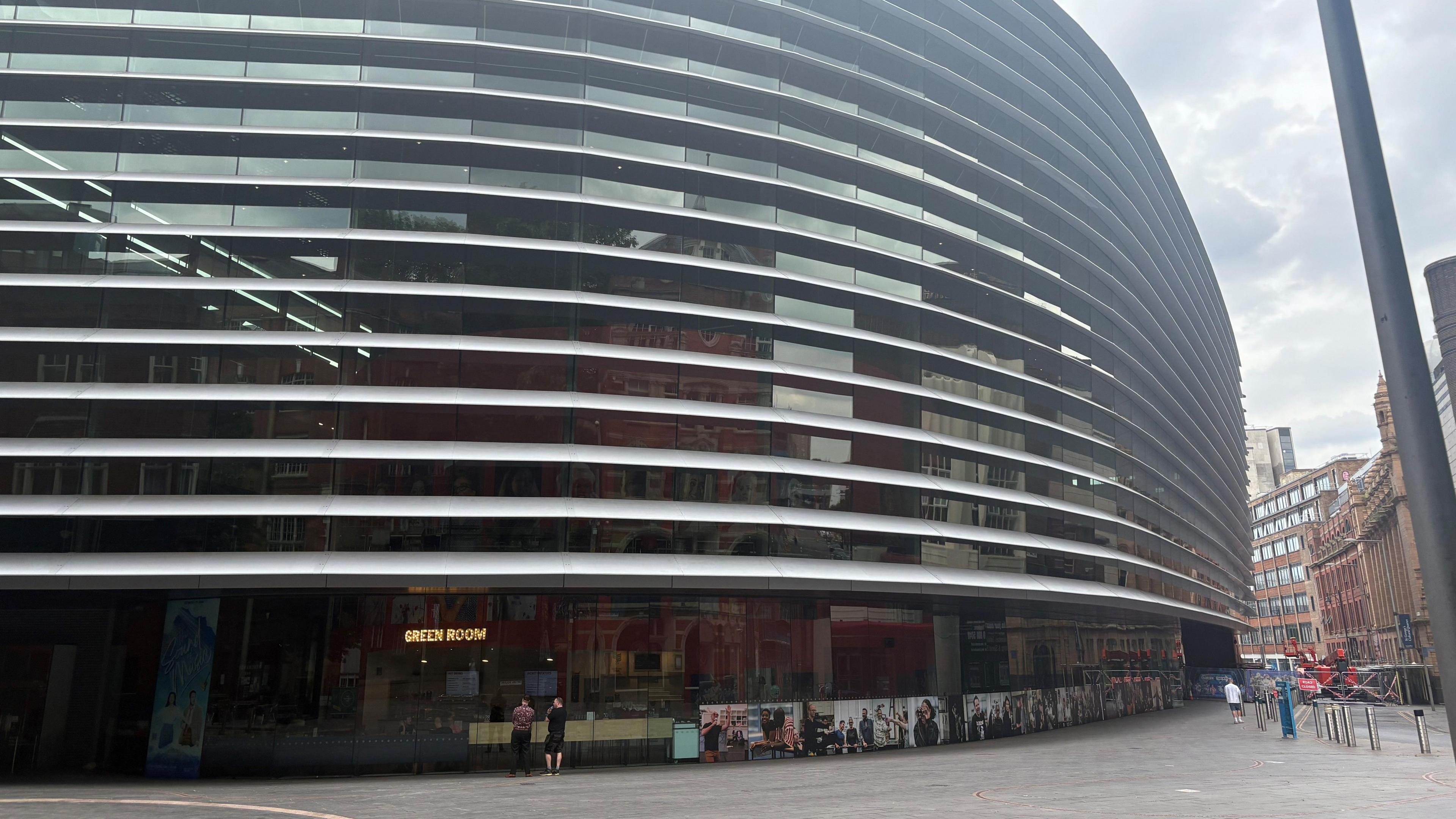 The outside of a tall theatre building in Leicester with grey panels between windows.