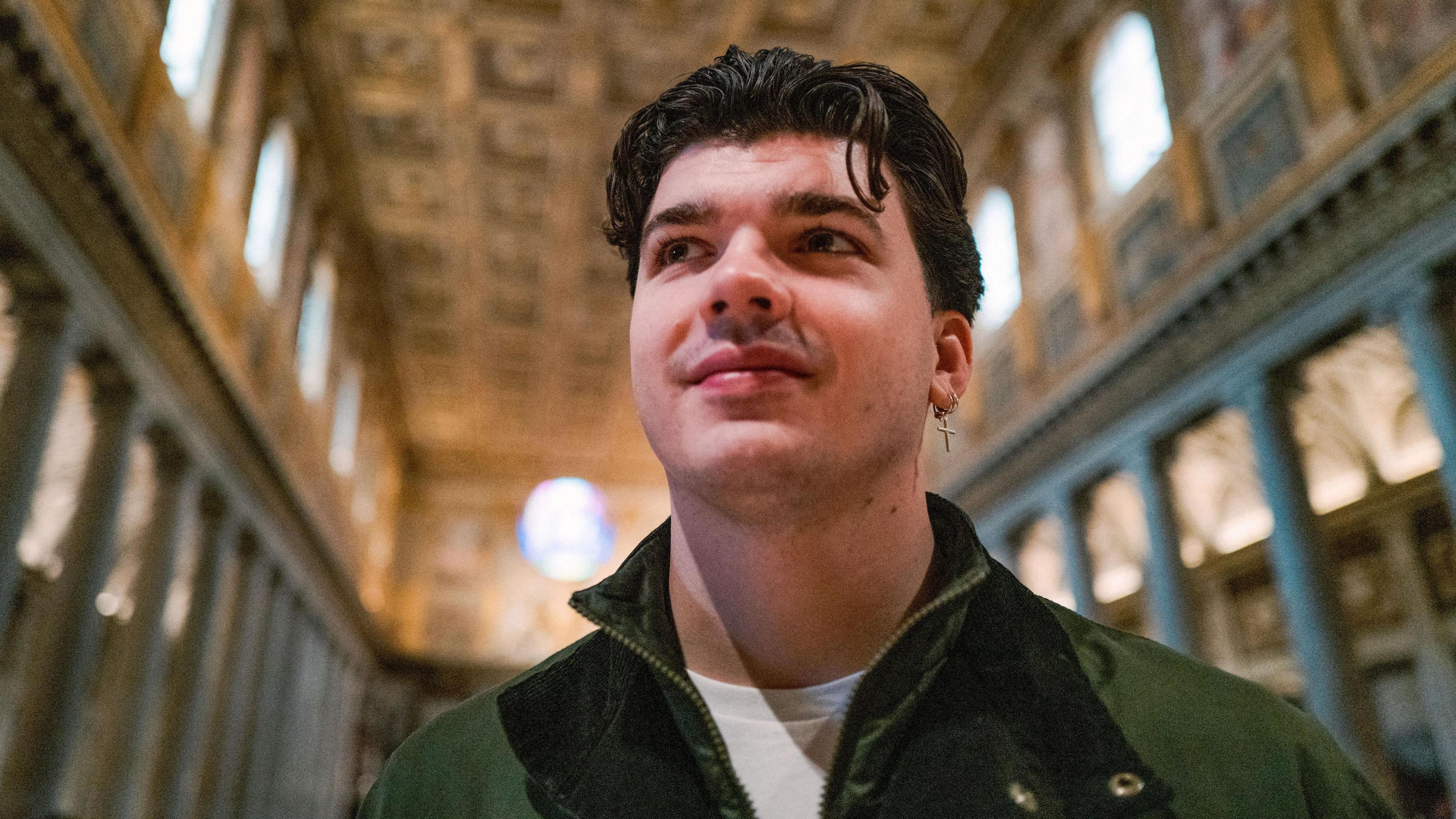 Harry Clark stands in a green jacked and white shirt looking up at a ceiling in a church in Rome