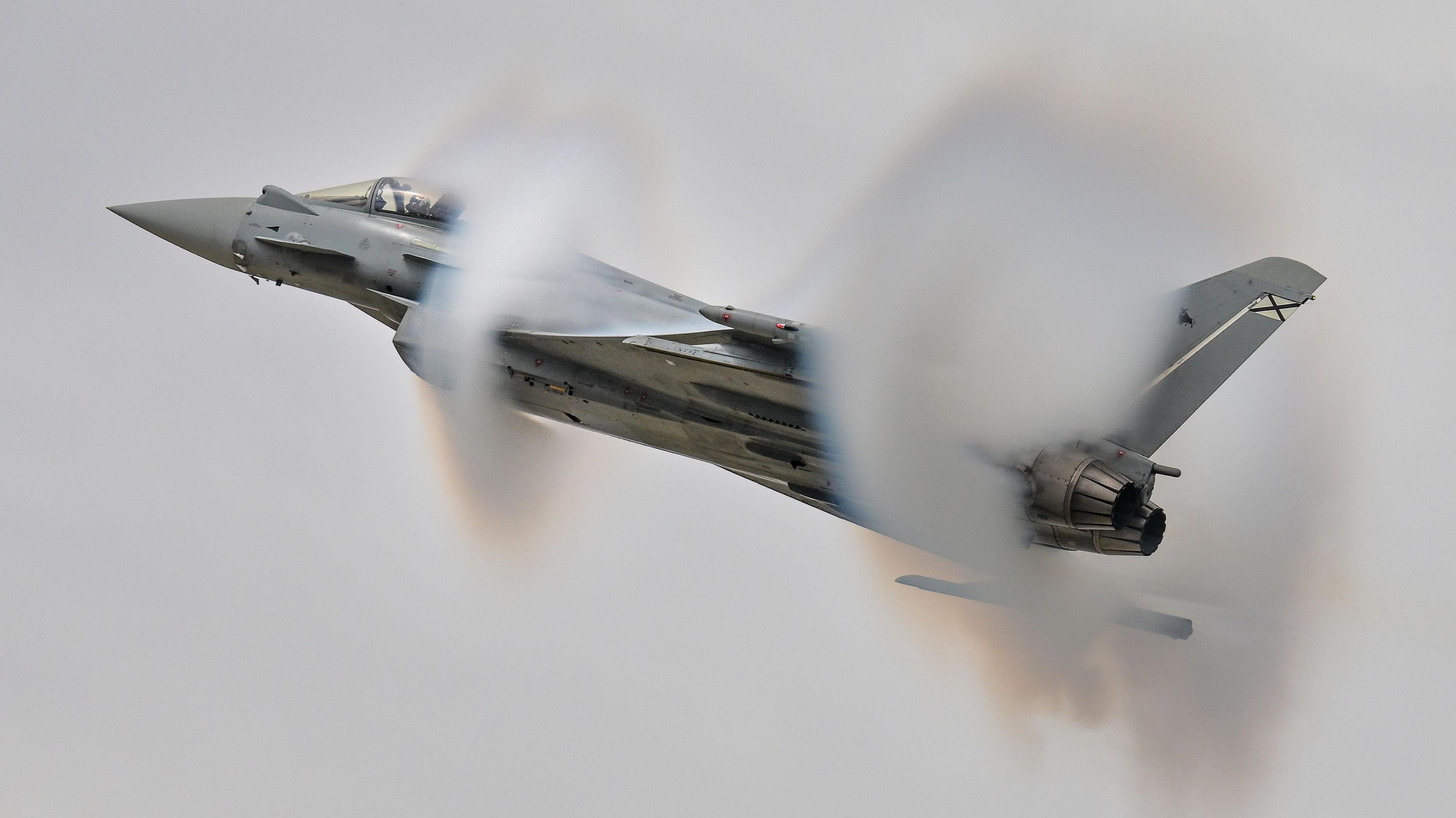The Spanish Air & Space Force Eurofighter C.16 Typhoon from Ala 14 creates moisture clouds around its wings and fuselage as it performs during the Royal International Air Tattoo at RAF Fairford.