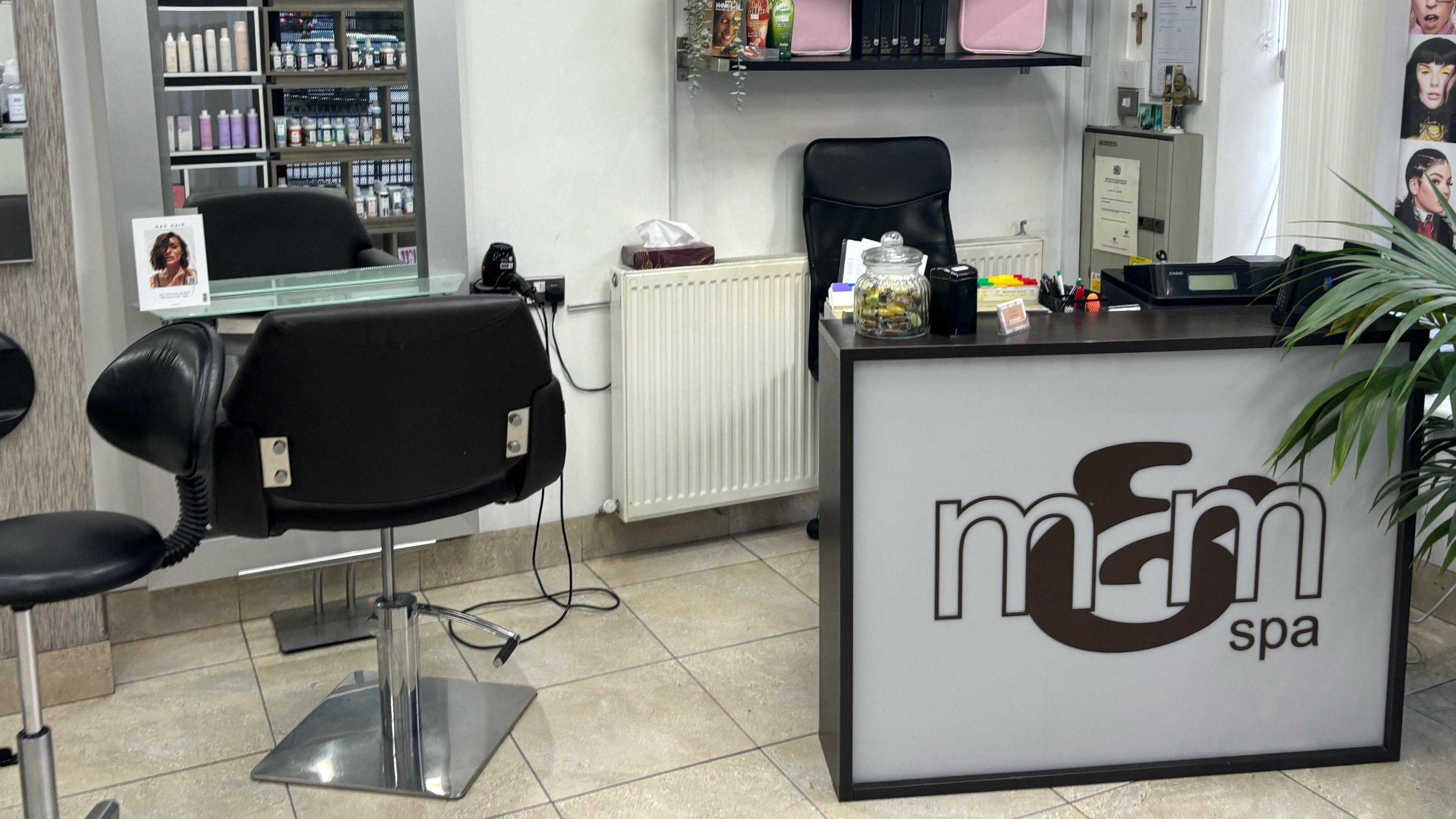 A hair salon that is black and white with a big M&M Logo on the main desk. 